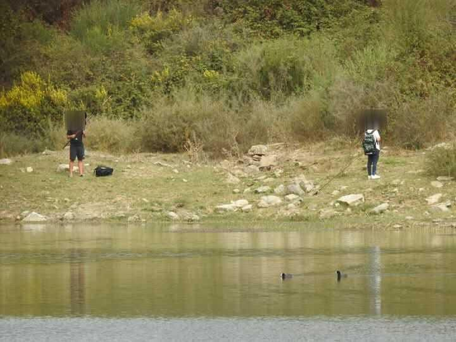 Dos personas con aparejos de pesca en la laguna, este fin de semana.
