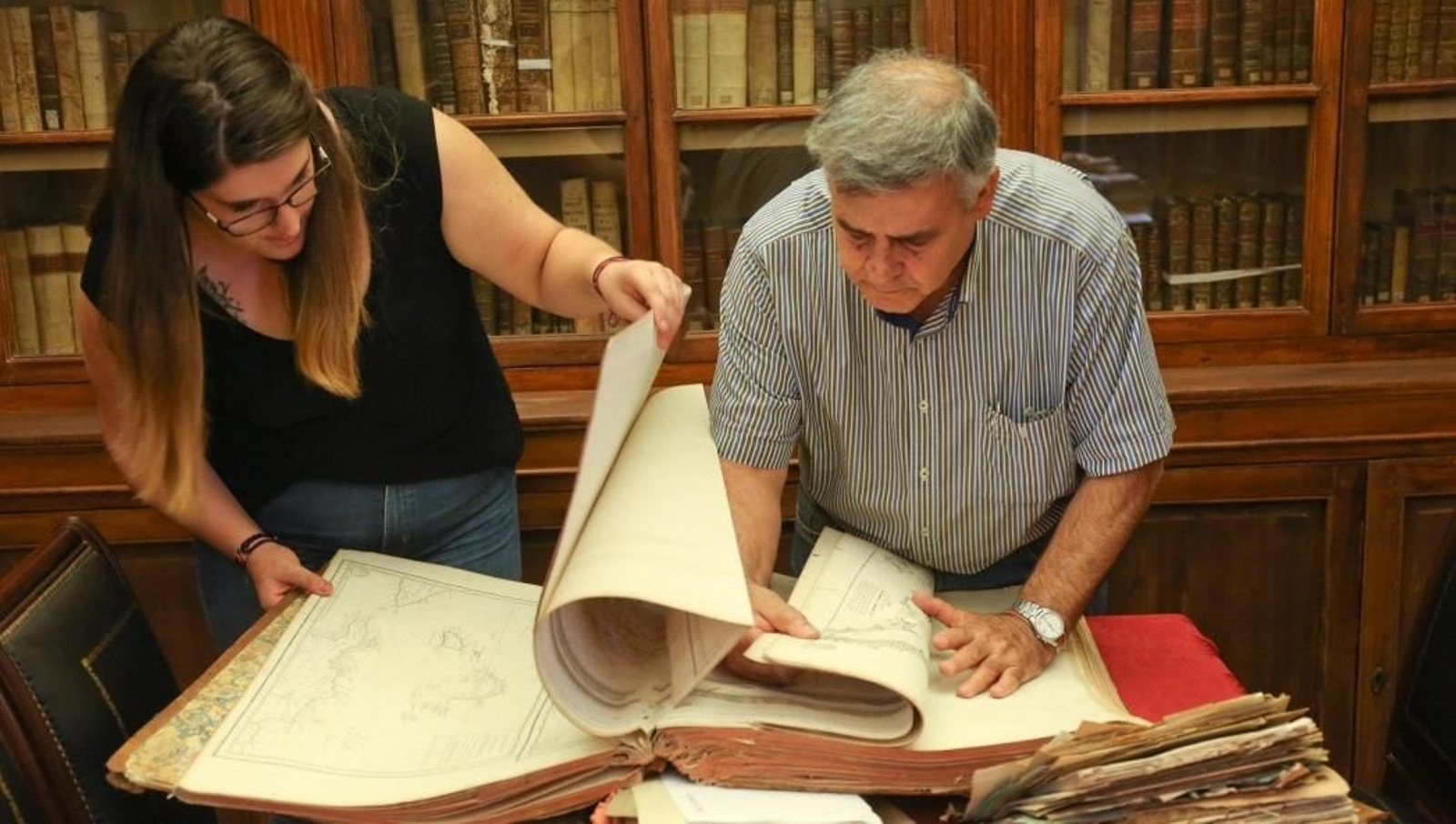 Lucía Reigal y Felipe Pajares consultan un atlas cartográfico de navegación del siglo XVIII. Lucía Reigal y Felipe Pajares consultan un atlas cartográfico de navegación del siglo XVIII.