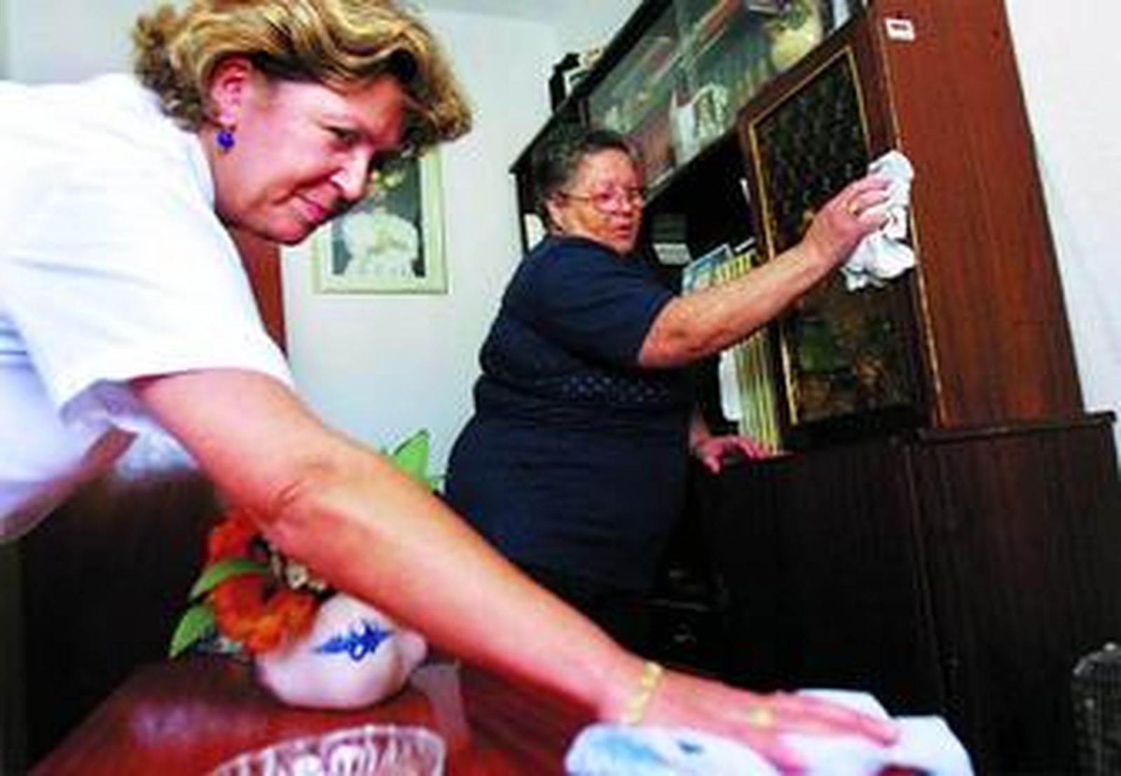 Una mujer del servicio de ayuda domiciliaria cumple su cometido junto a la anciana beneficiaria del mismo.