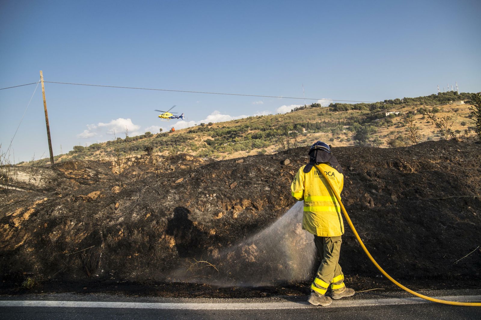 Un bombero del Infoca, durante las labores de extinción del incendio de El Fargue en la carretera de Víznar.