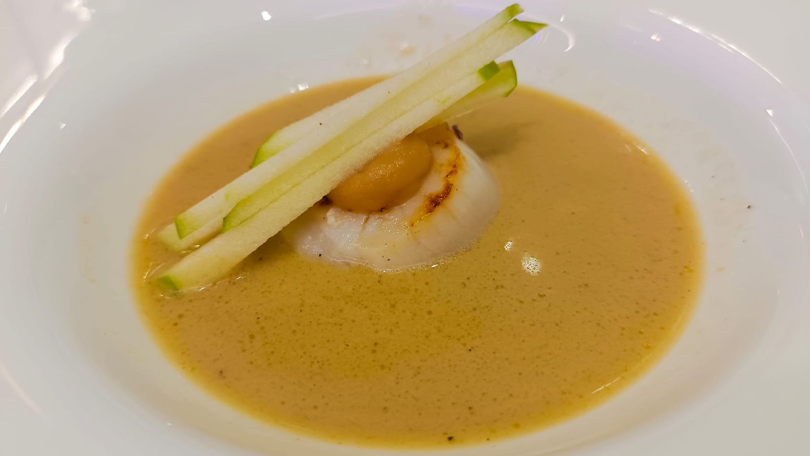 La vieira servida con salsa de foie-gras y manzana verde.
