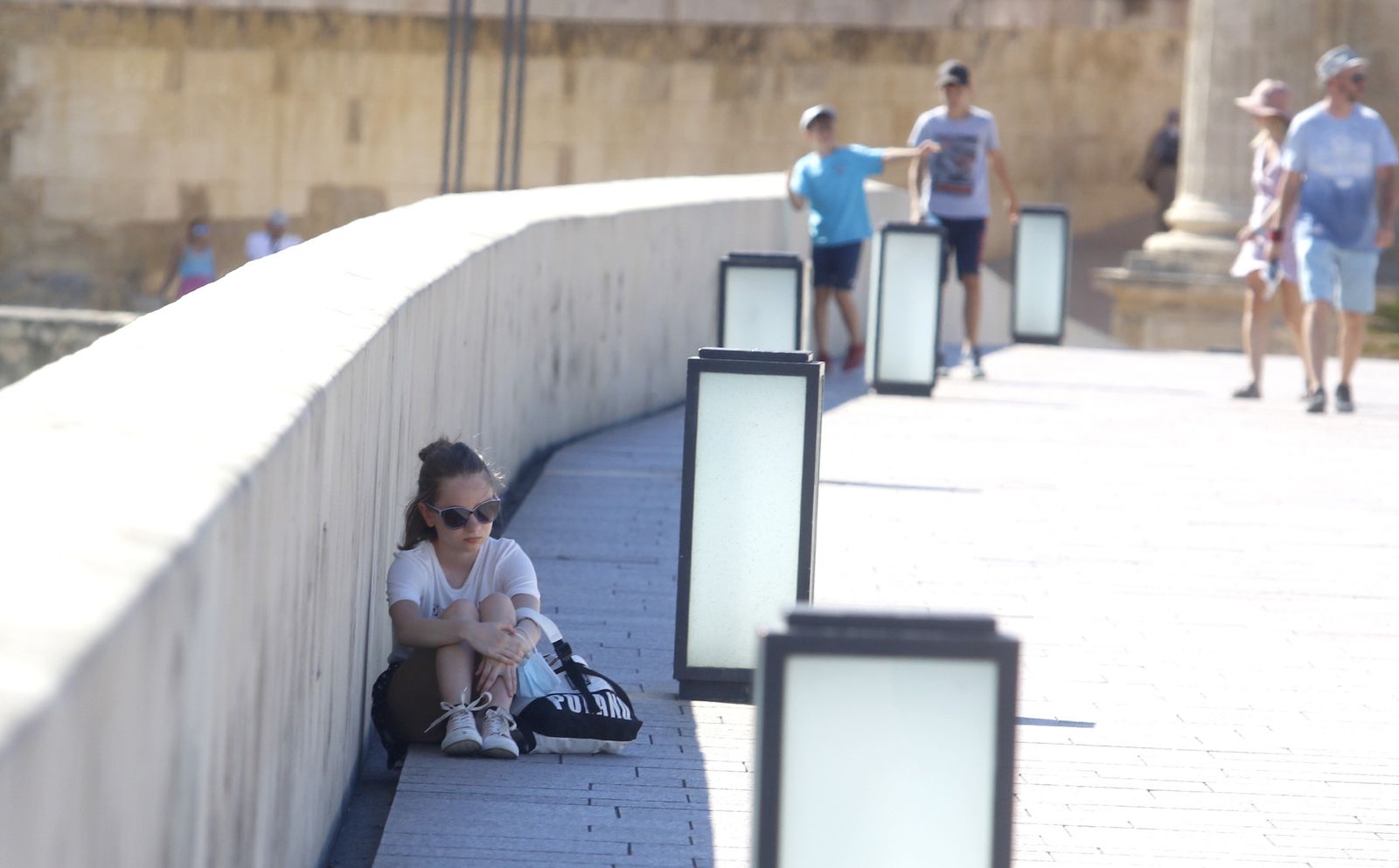 Una persona se refugia en la sombra en el Puente Romano.
