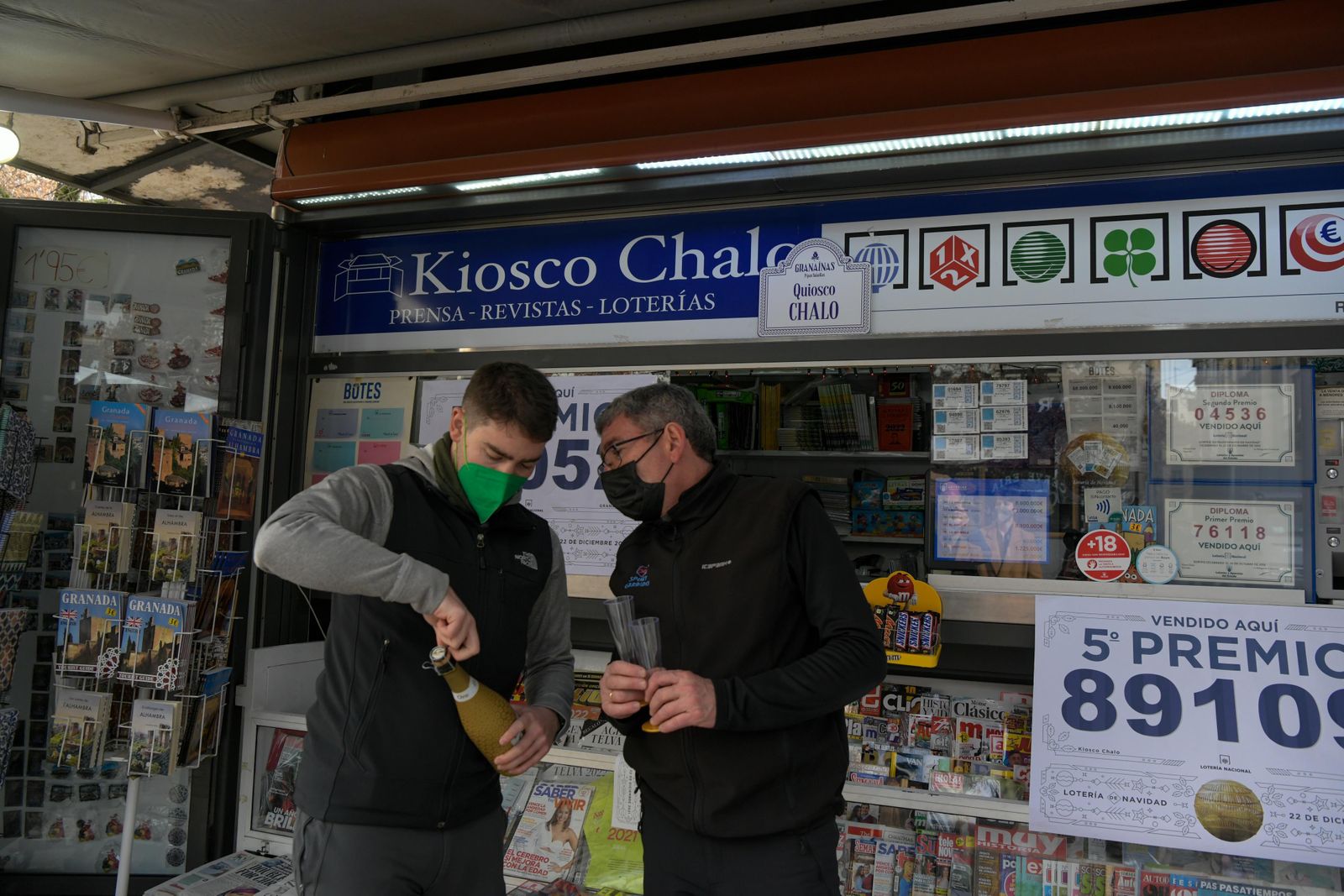 Lotero e hijo, regentes del Kiosko Chalo de Granada, brindan tras dar dos quintos en la Lotería de Navidad.