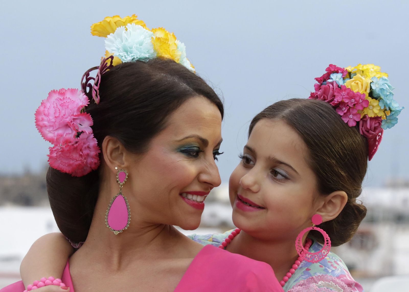 Madre e hija con flores en forma de ramillete de muchos colores.