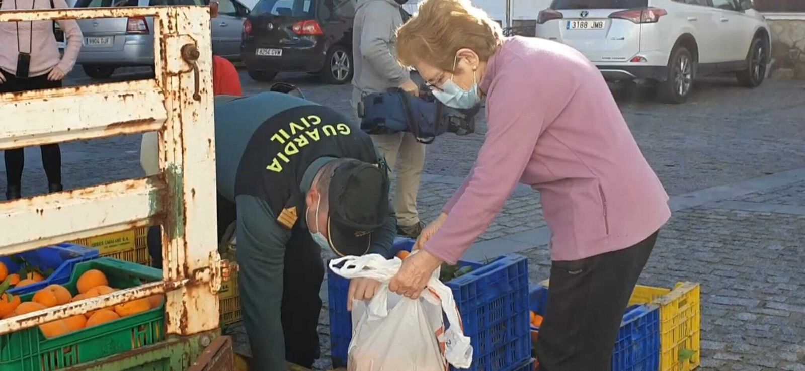 Un agente entrega naranjas a una vecina en la Plaza Alta.