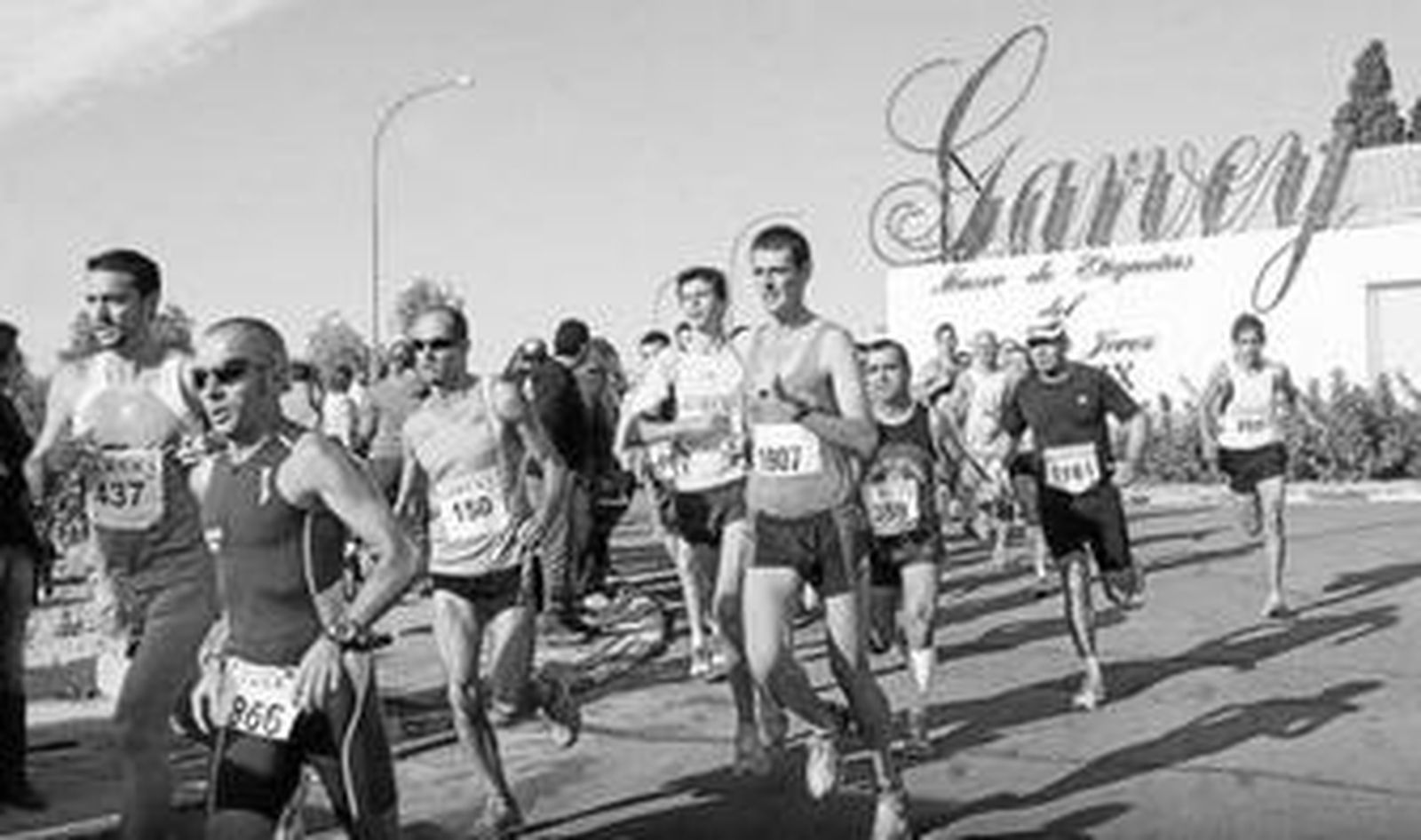 Un grupo de participantes en la prueba, con la bodega patrocinadora al fondo.