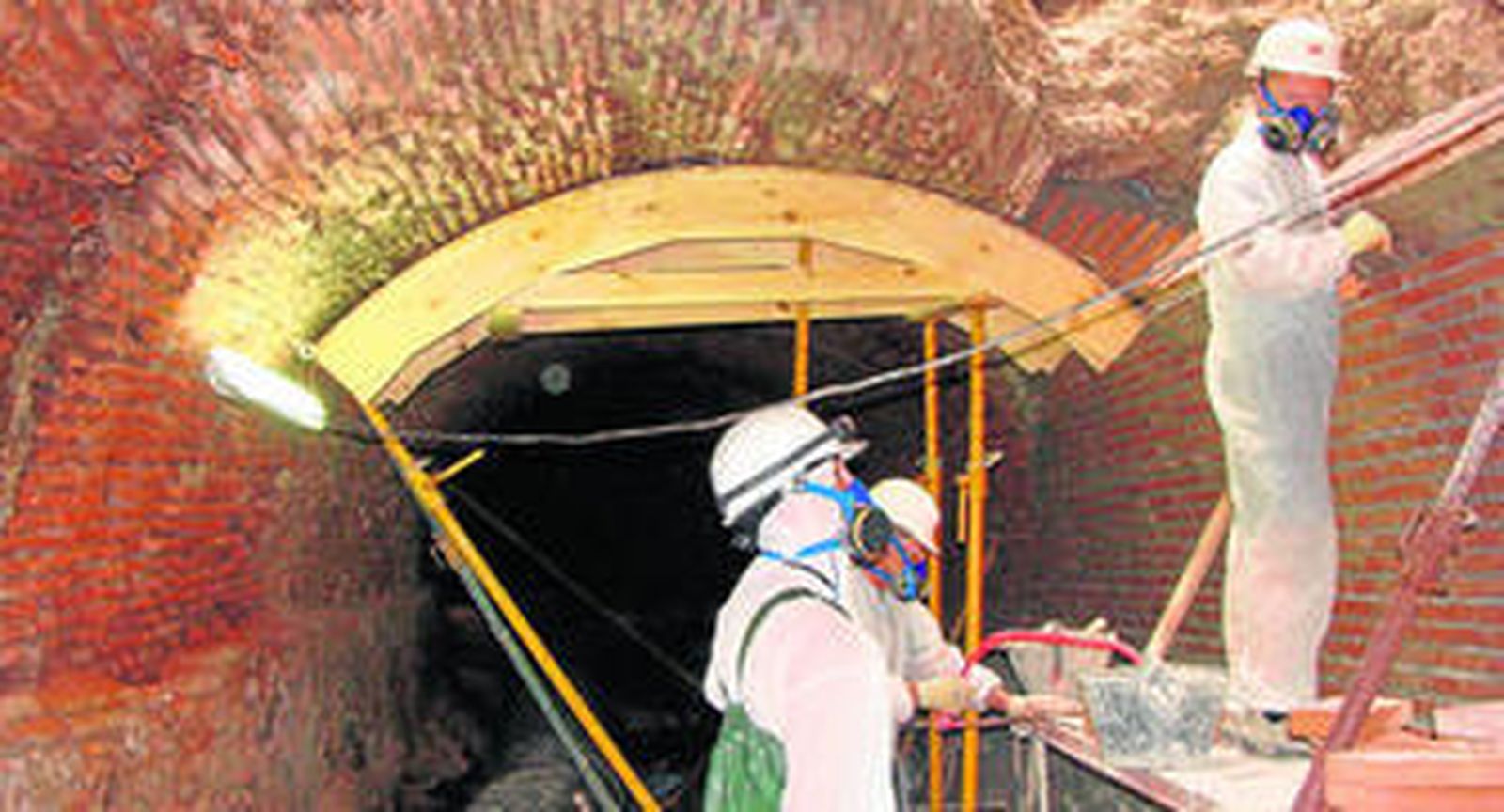 1. Técnicos inspeccionan el interior del colector durante las obras de restauración que se llevaron a cabo en agosto de 2013. 2. Interior del colector que discurre por todo el trazado de la calle Carretería y que fue construido sobre el foso de la antigua muralla originaria de época árabe. . 3. Cubrimiento con ladrillo del tramo de la muralla que había quedado al descubierto tras el derrumbe de parte de la bóveda. 4. Empleados, en el interior.