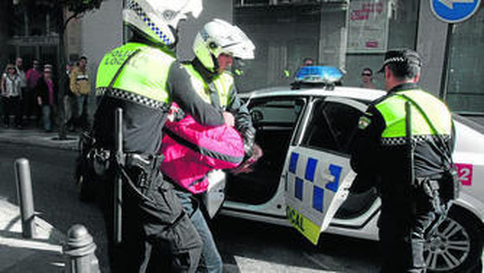 Los policías introducen al detenido en un coche patrulla tras lograr alcanzarlo.