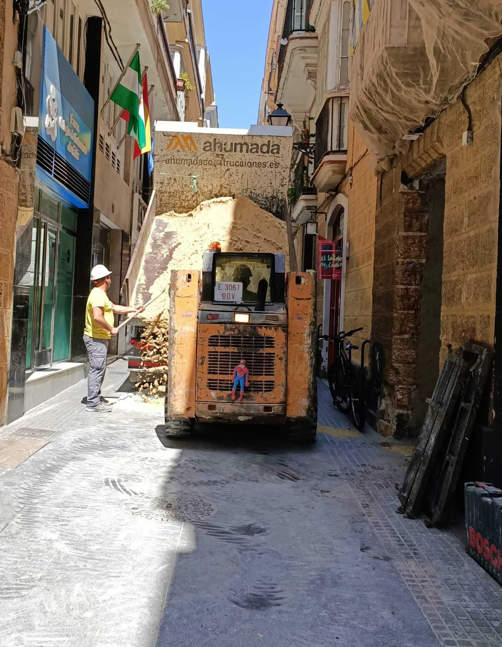 Una máquina, ayudando a descargar el camión delante de la puerta de la tienda.