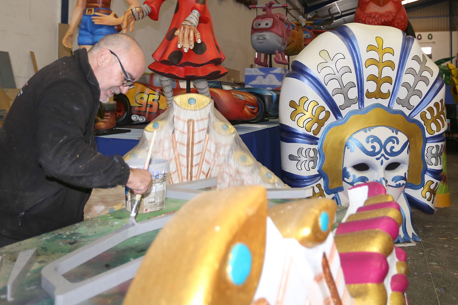 Un operario trabaja en la decoración de una carroza con motivos carnavalescos.