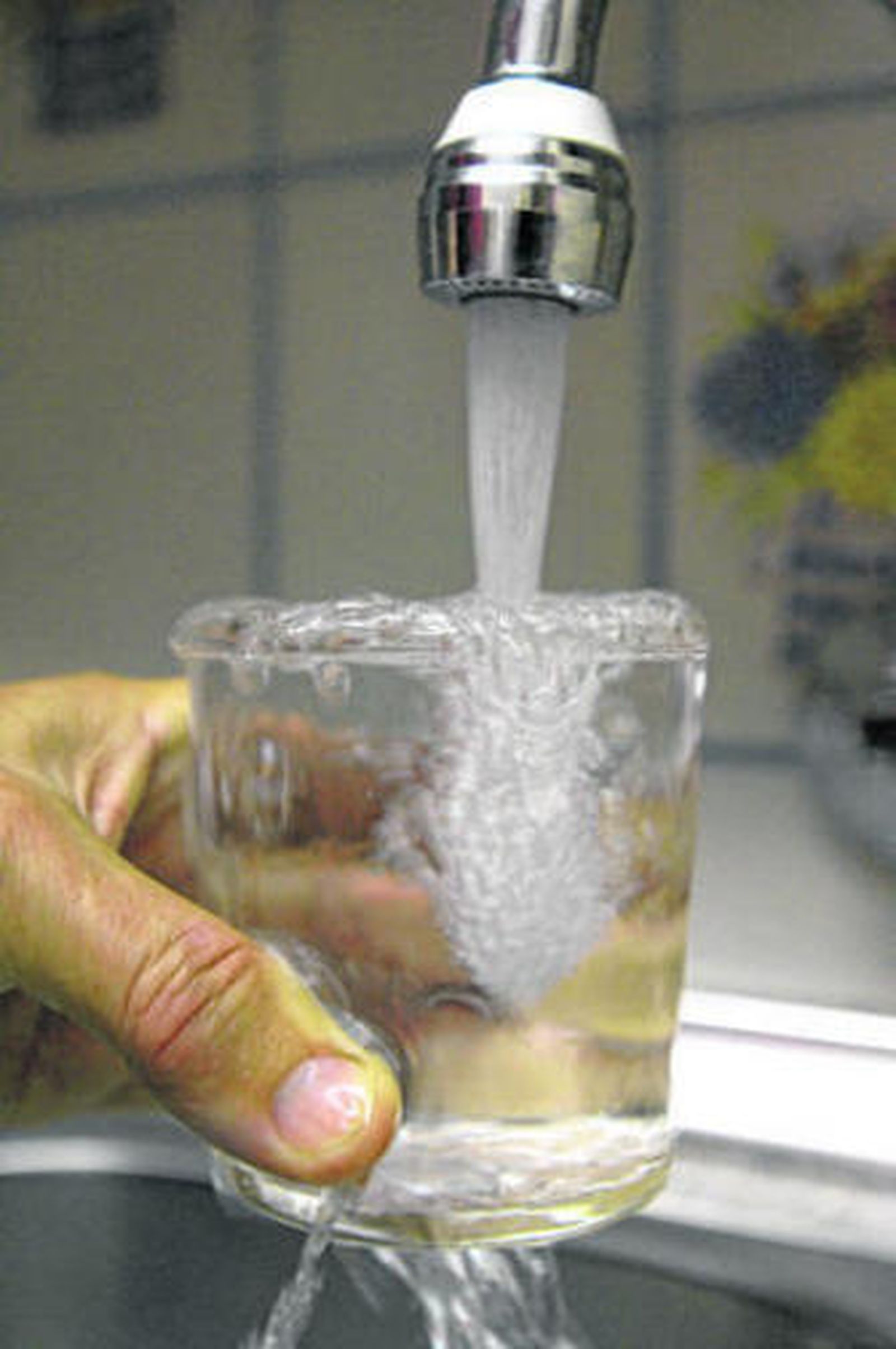 Grifo de agua abierto para llenar un vaso.