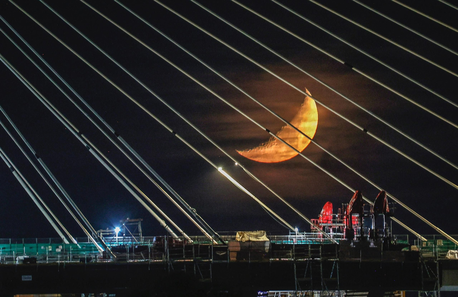 El puente del Centenario de noche, con la luna de fondo.