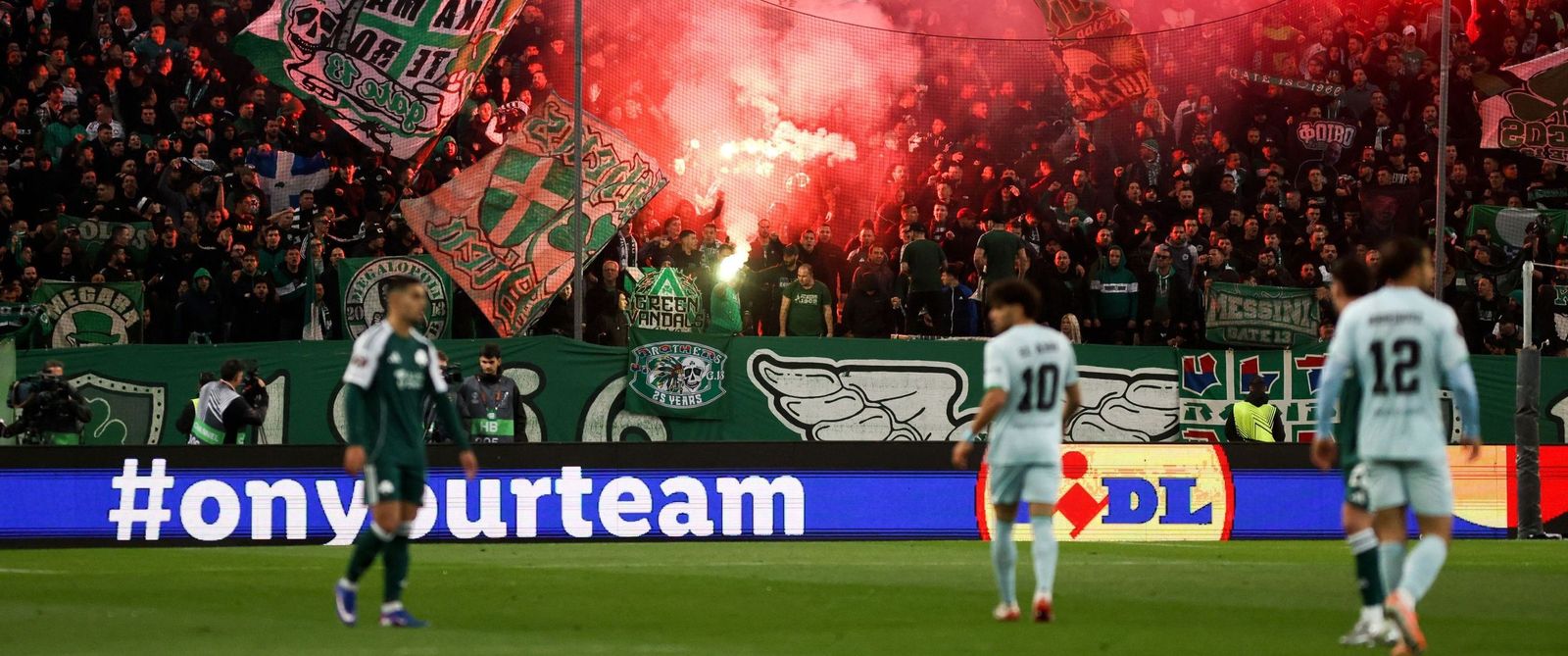 Una imagen del partido con las tradicionales bengalas en los estadios griegos al fondo.