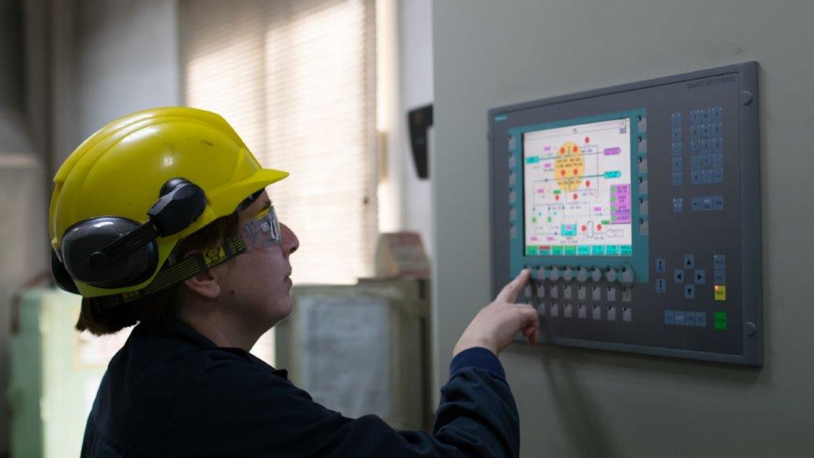 Una operadora realiza unos ajustes en un panel de mandos de la factoría.