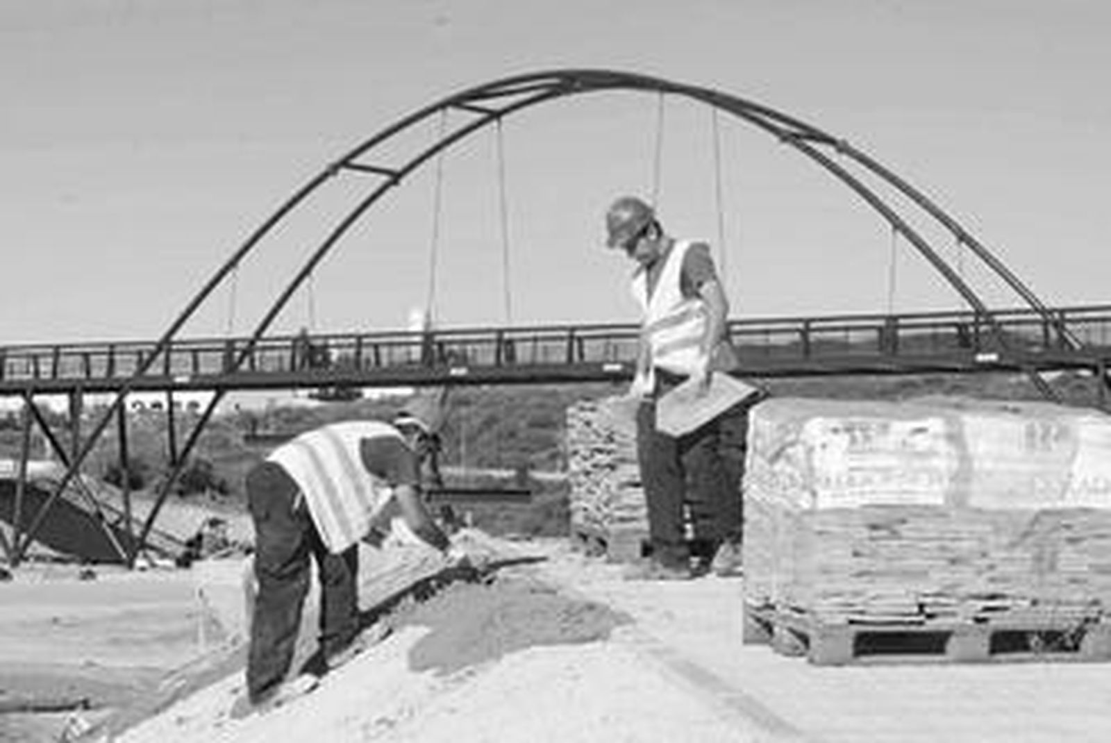 Dos operarios trabajan en los accesos al nuevo puente de Miraflores.