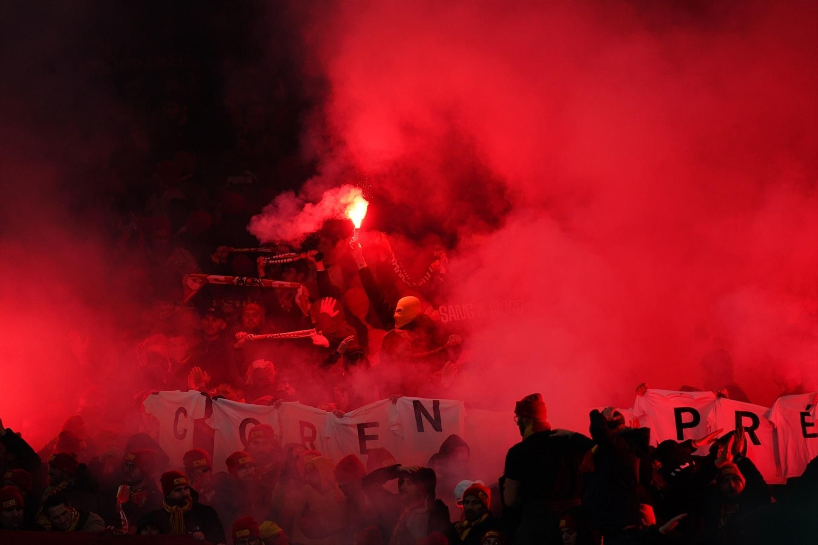 Hinchas del Lens encienden bengalas en la reciente visita del equipo al Arsenal en Londres.