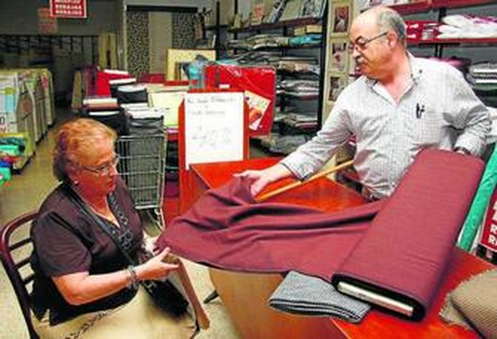 1. Imagen del almacén, que antes cogía casi toda la calle Puente  y Pellón, con los carteles en la puerta anunciando su cierre               2. Alfonso Viejo atiende a la que será su última clienta, Antonia Gassin, que está sentada en una silla de madera emblemática    3. El dependiente muestra las estanterías vacías