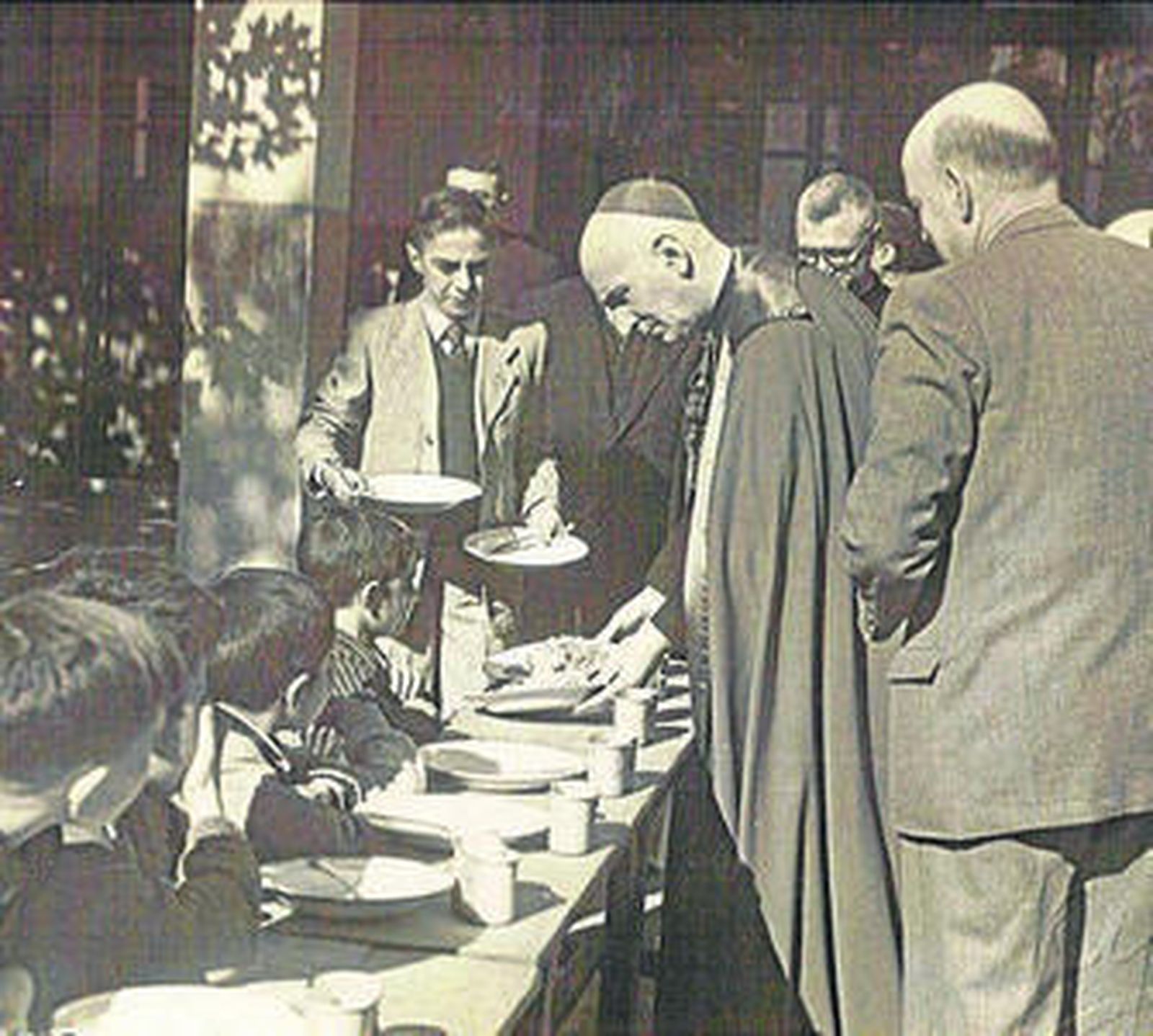 El cardenal Herrera Oria reparte alimentos a niños de las escuelas Ave María en 1957.