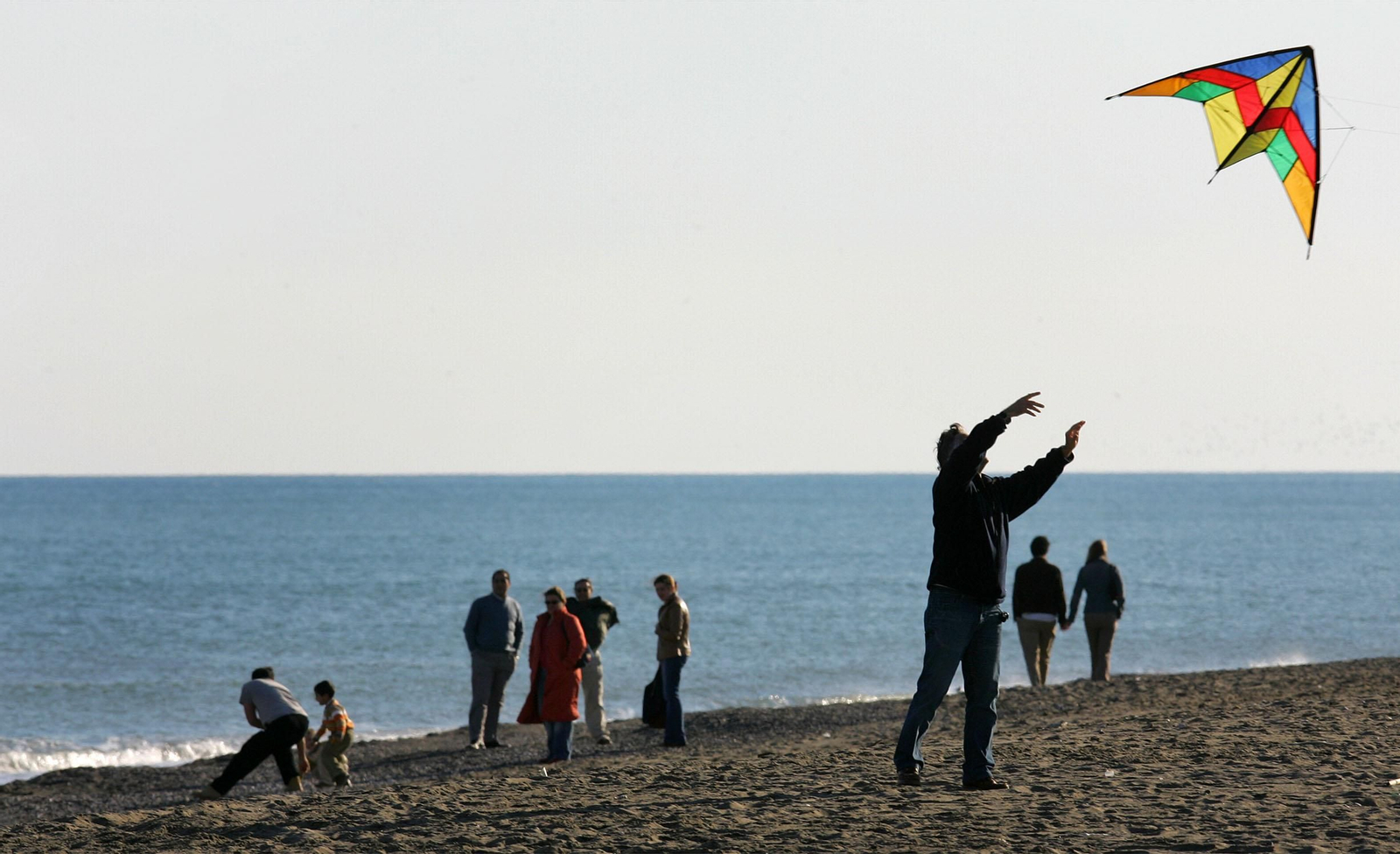 Una persona volando una cometa en la playa