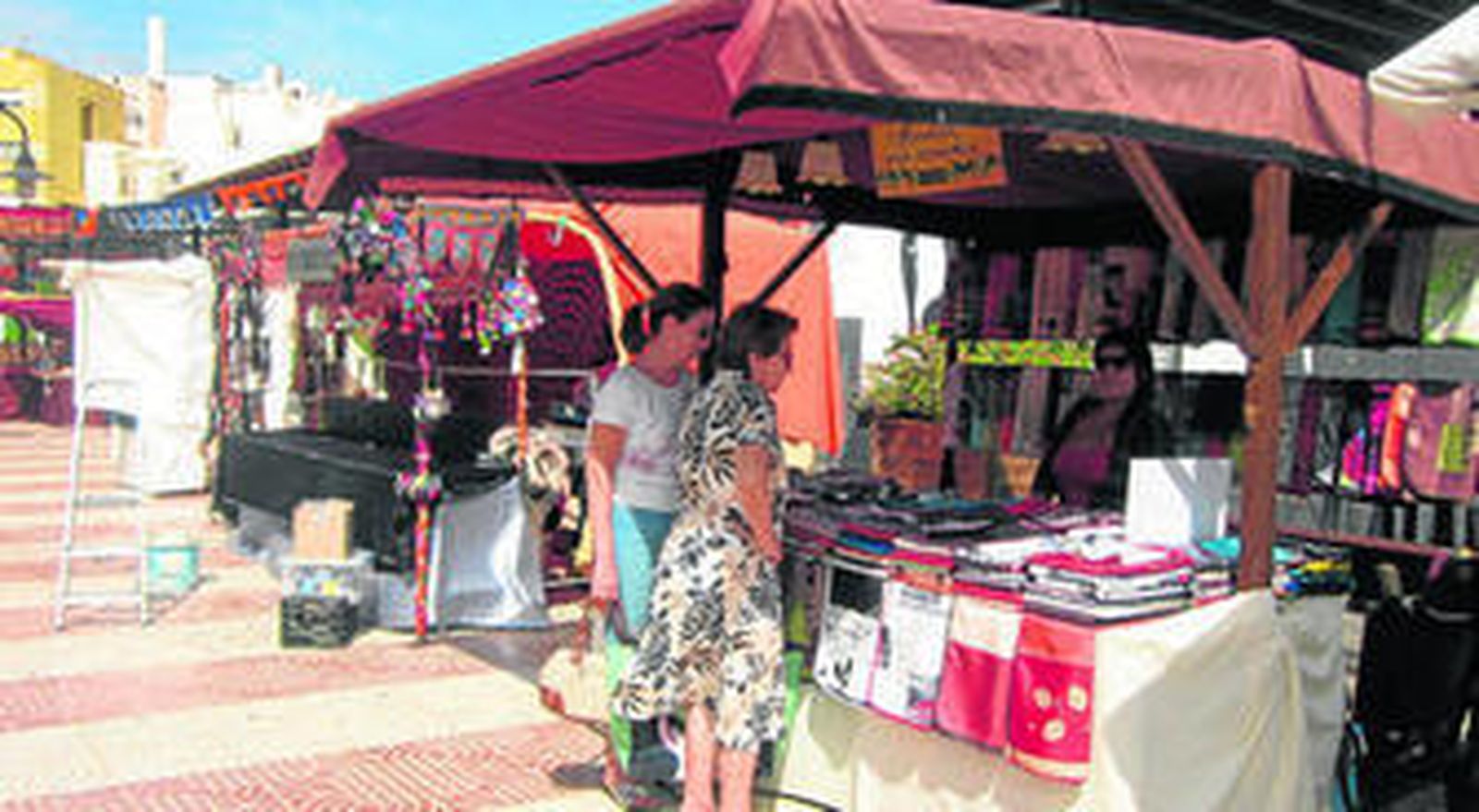 Dos vecinas del municipio se interesaron por conocer las propiedades de los manteles antimanchas que se venden en este puesto.