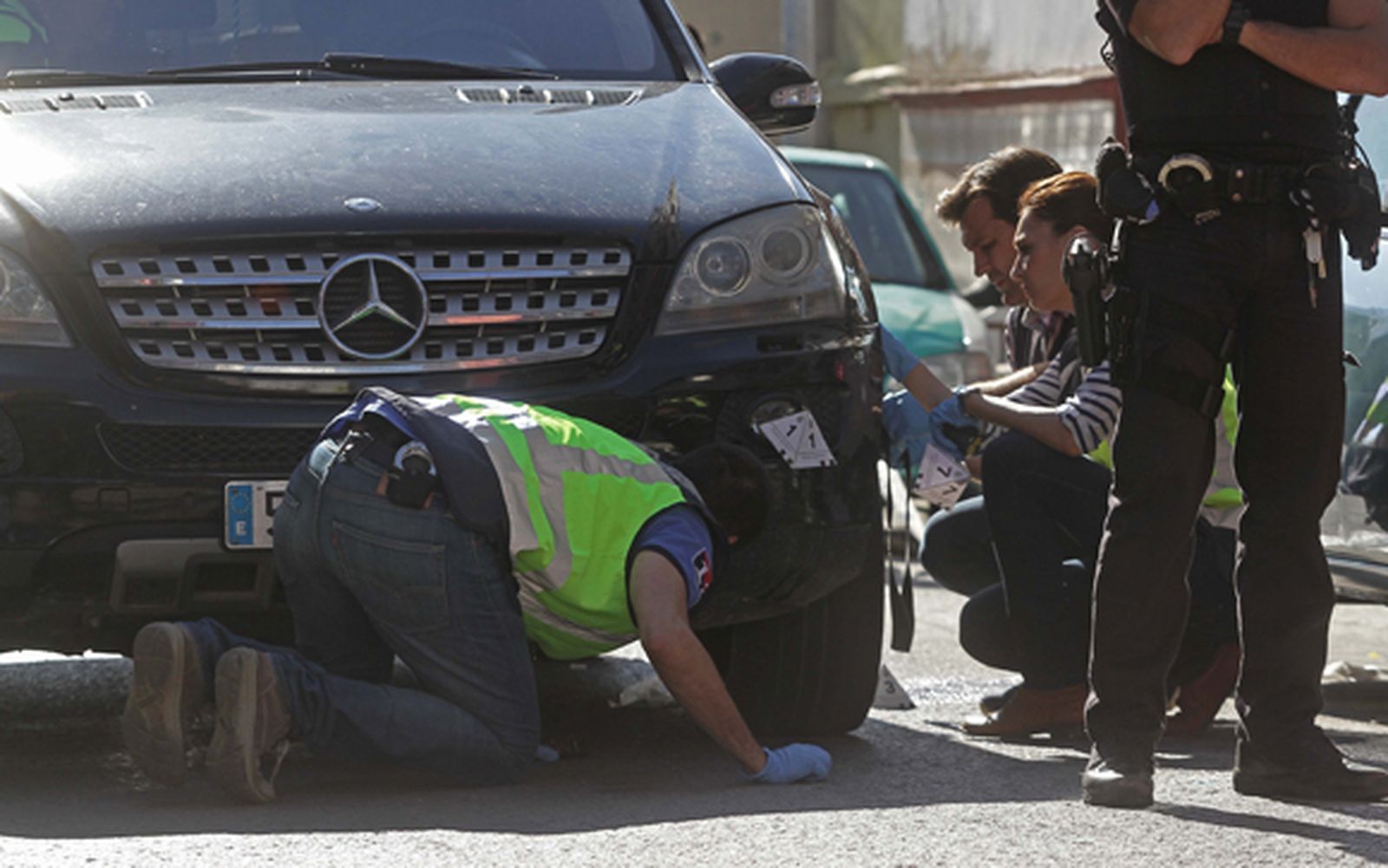 Los agentes de la Policía Científica, inspeccionando los bajos del coche que originó el accidente de ayer. /Erasmo Fenoy