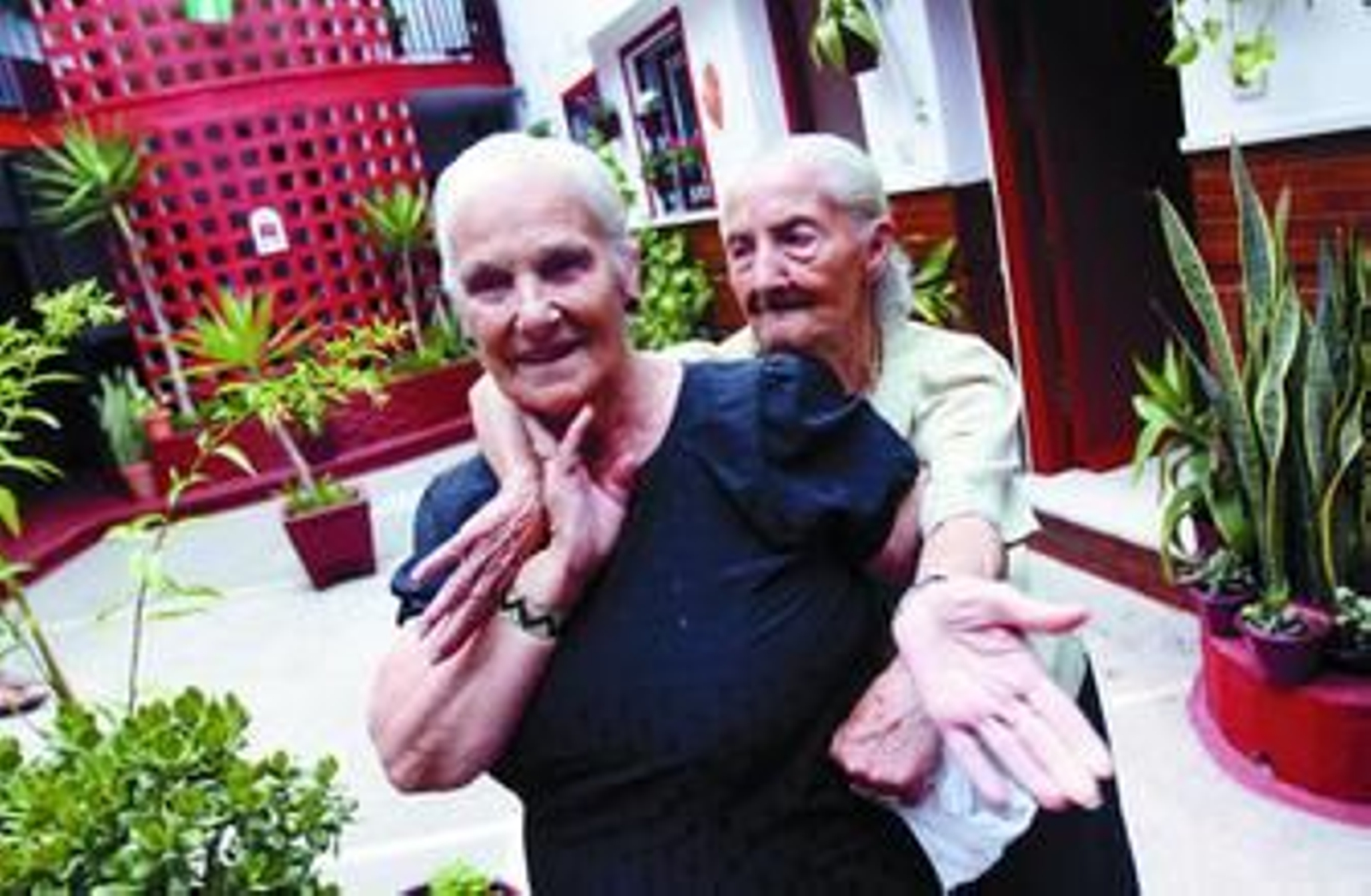 María Recio, en su corralón de la calle Agustín Parejo, abrazada por su vecina.