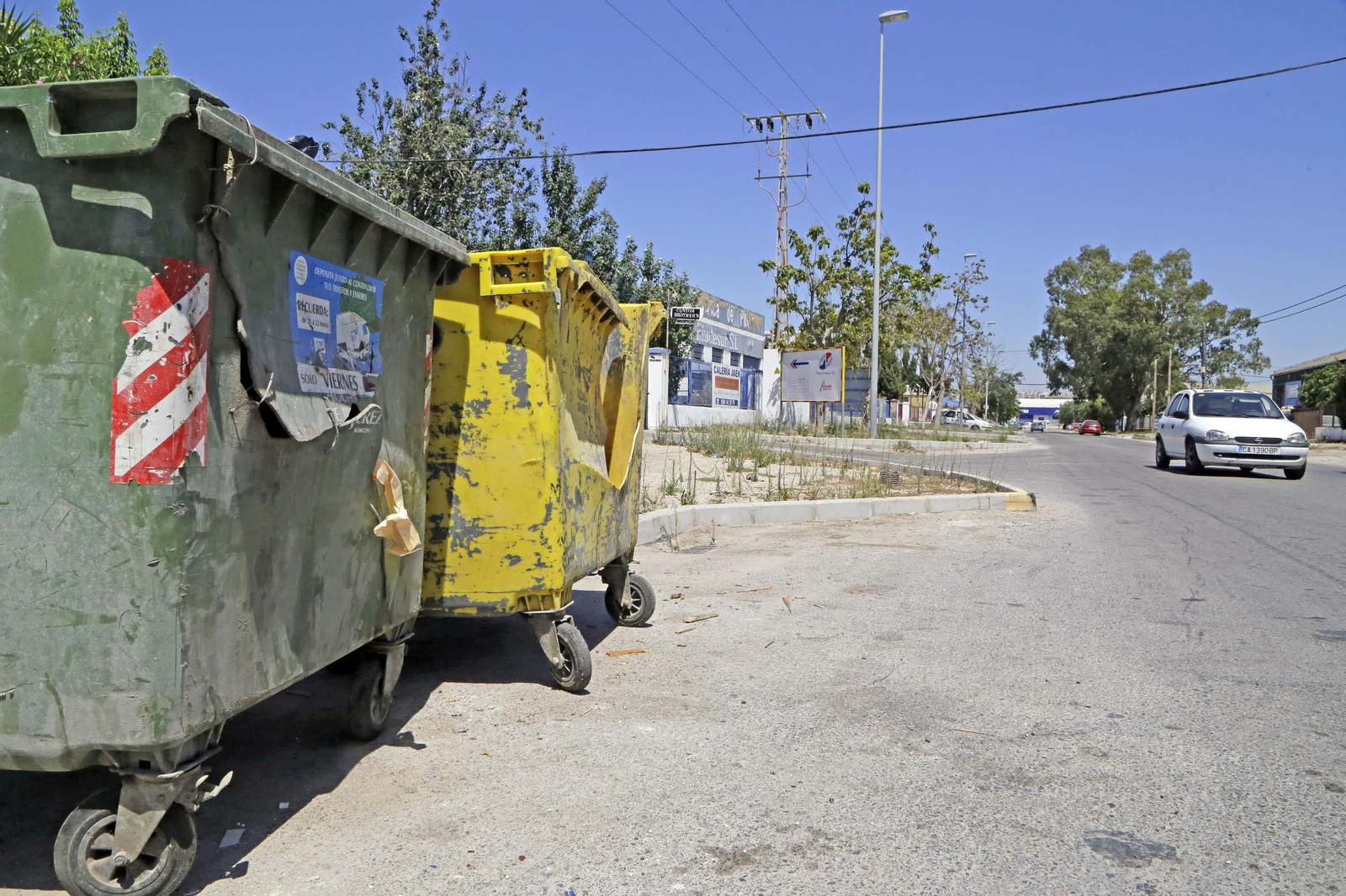 Dos contenedores de basura en estado defectuoso en una de las vías alternativas del polígono industrial de El Portal