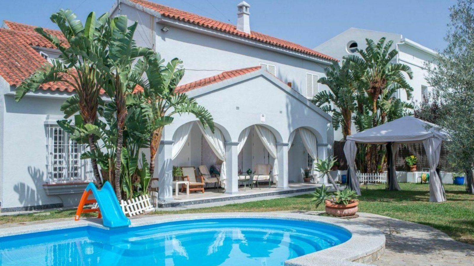 Piscina y acceso porticado a la vivienda.
