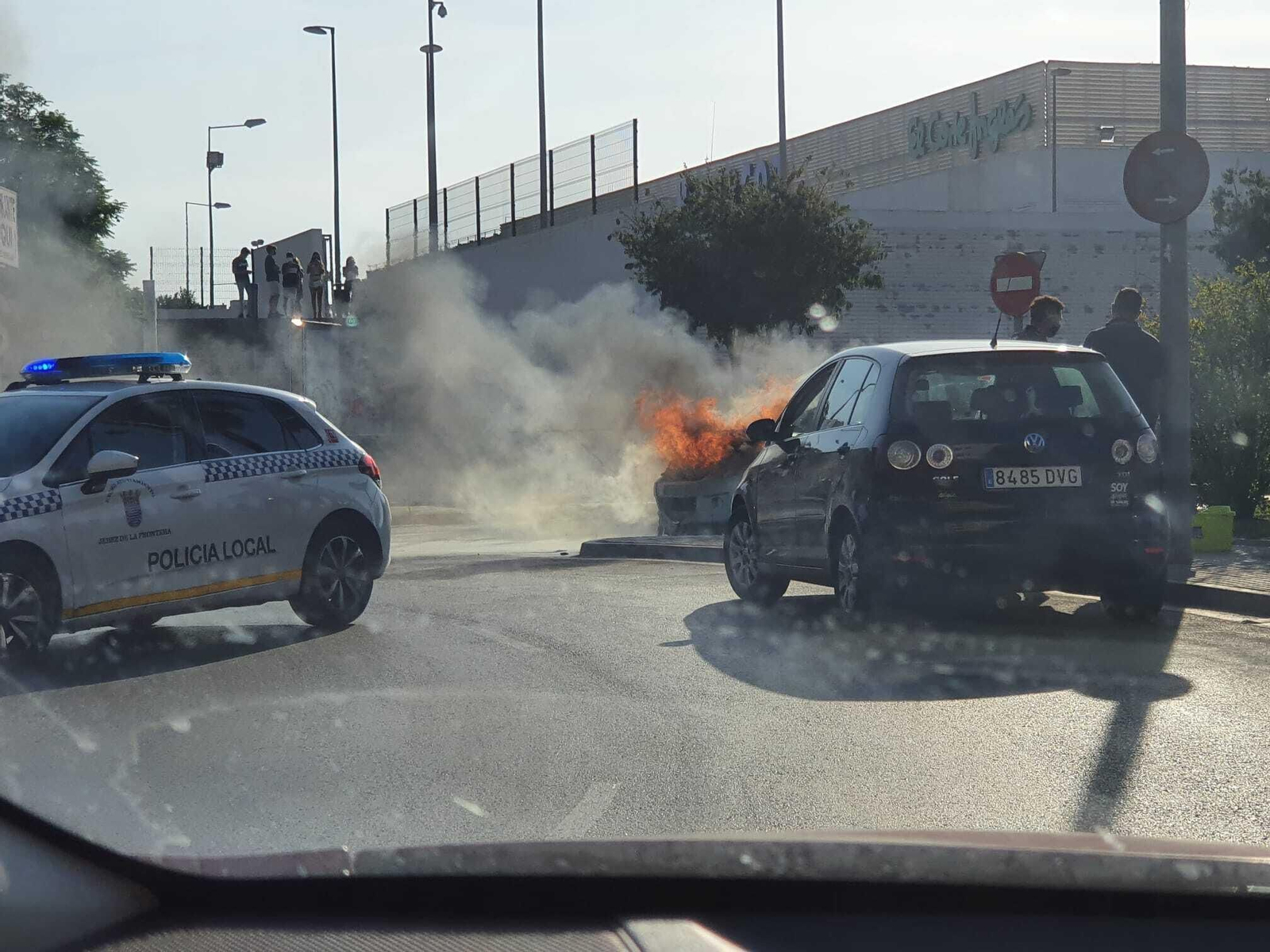 Un patrulla de la Policía Local junto al coche ardiendo.