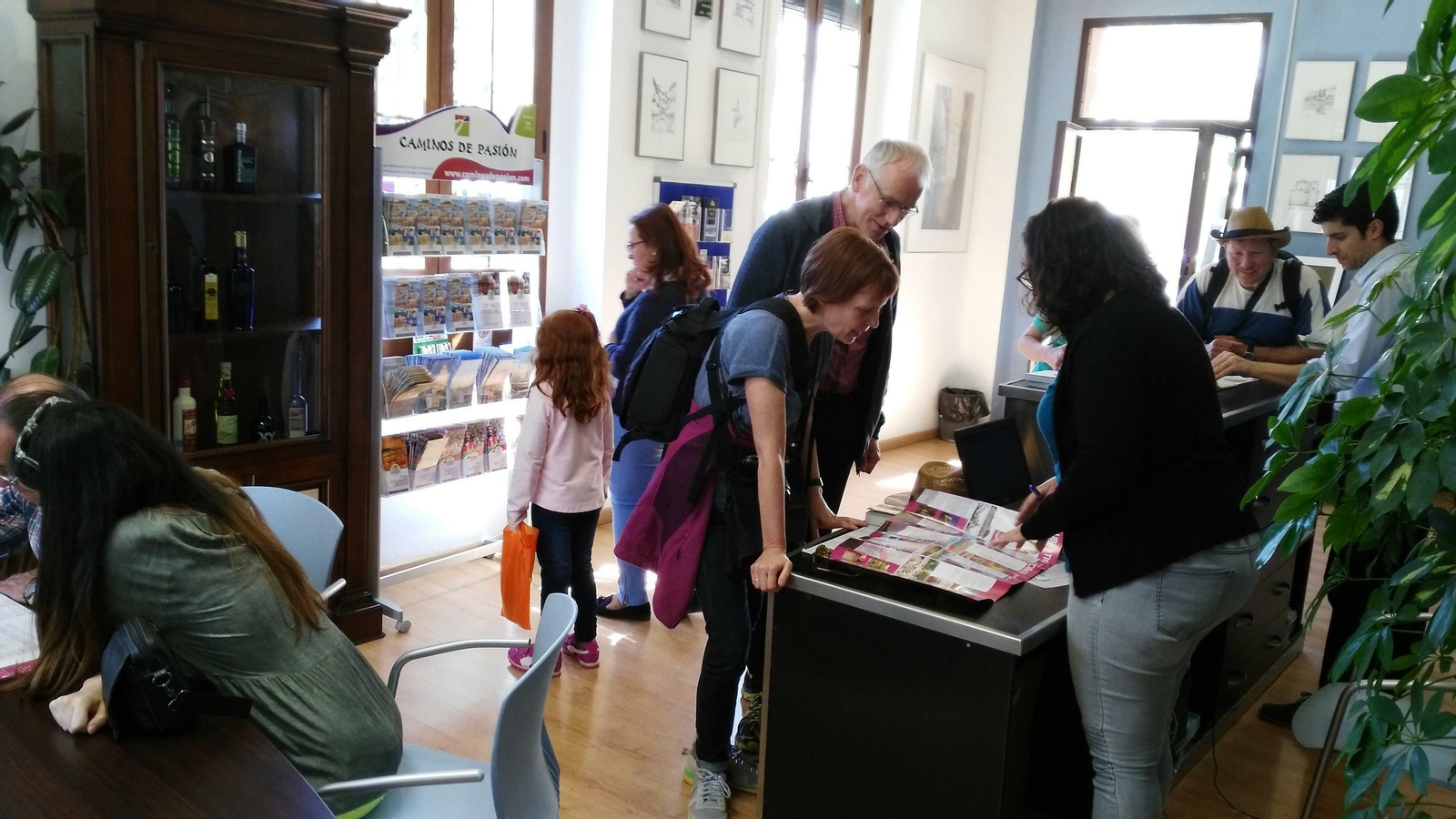 Unos turistas realizan una consulta en la oficina de información de Priego.