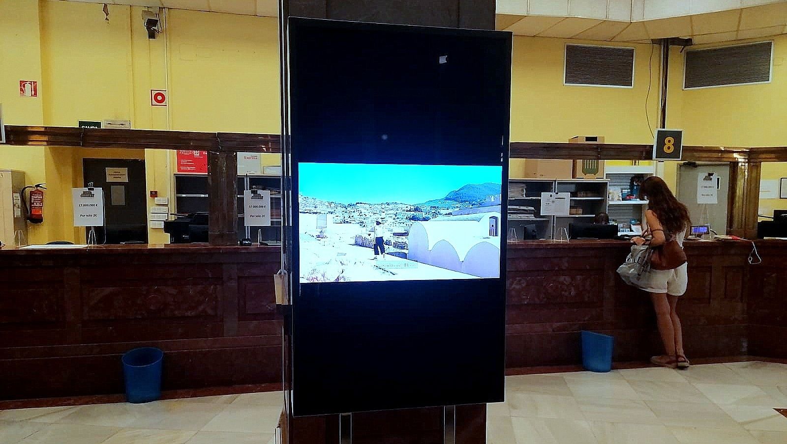 Una pantalla en una oficina de Correos muestra la promoción de Granada