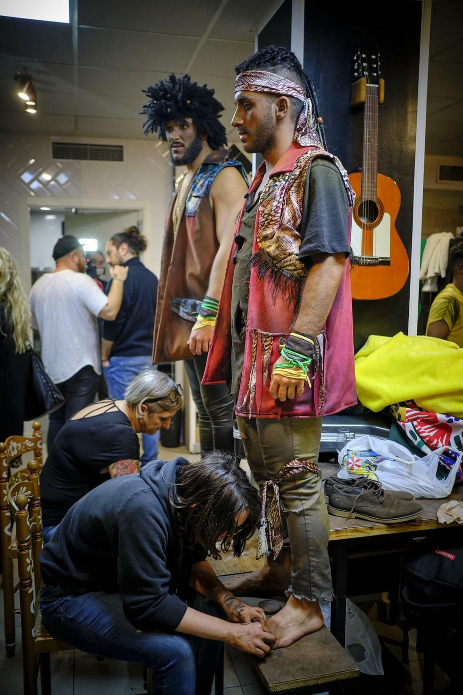 Dos componentes mientras le maquillan los pies descalzos.