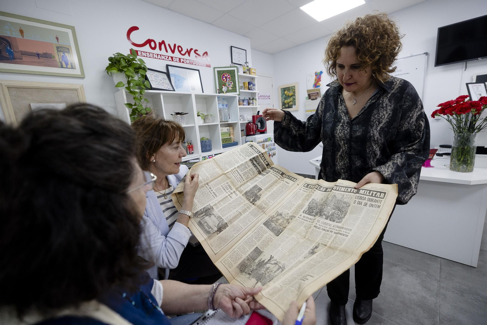 Mercedes Arias enseña a unas alumnas un periódico con una noticia sobre la Revolución de los Claveles.