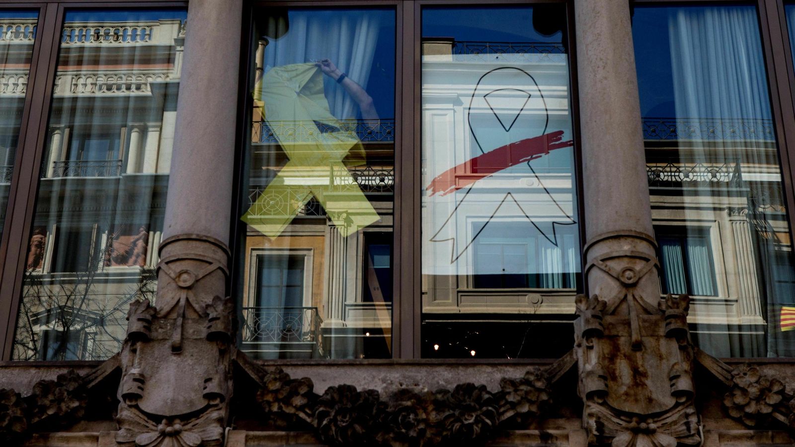 Un operario retira el lazo amarillo de una de las ventanas de la fachada del edificio de la Consellería de Economía tras sustituirlo por otro de color blanco conforme con el requerimiento de la Junta Electoral Central