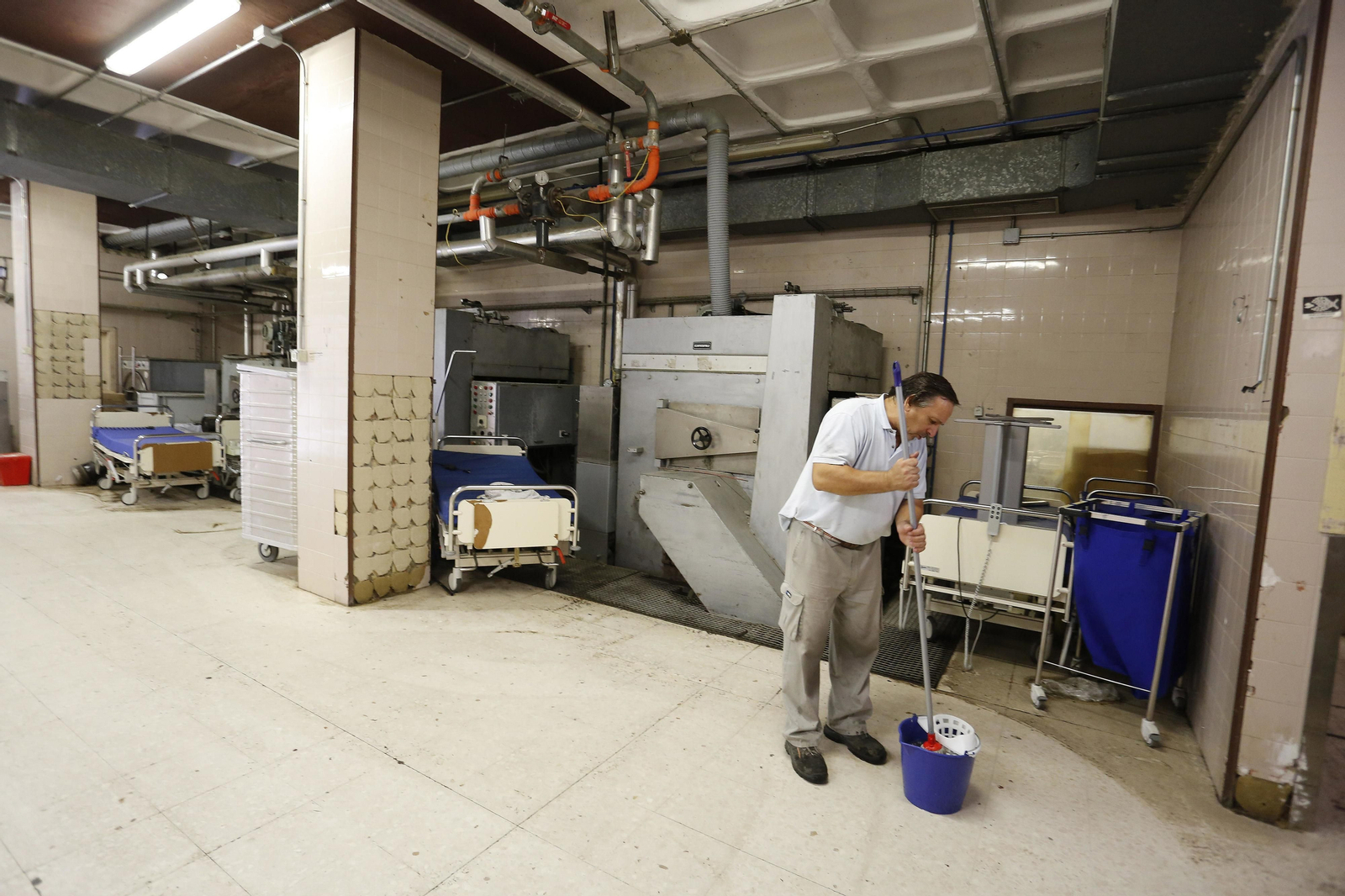 Un trabajador limpia, fregona en mano, las dependencias de la lavandería.