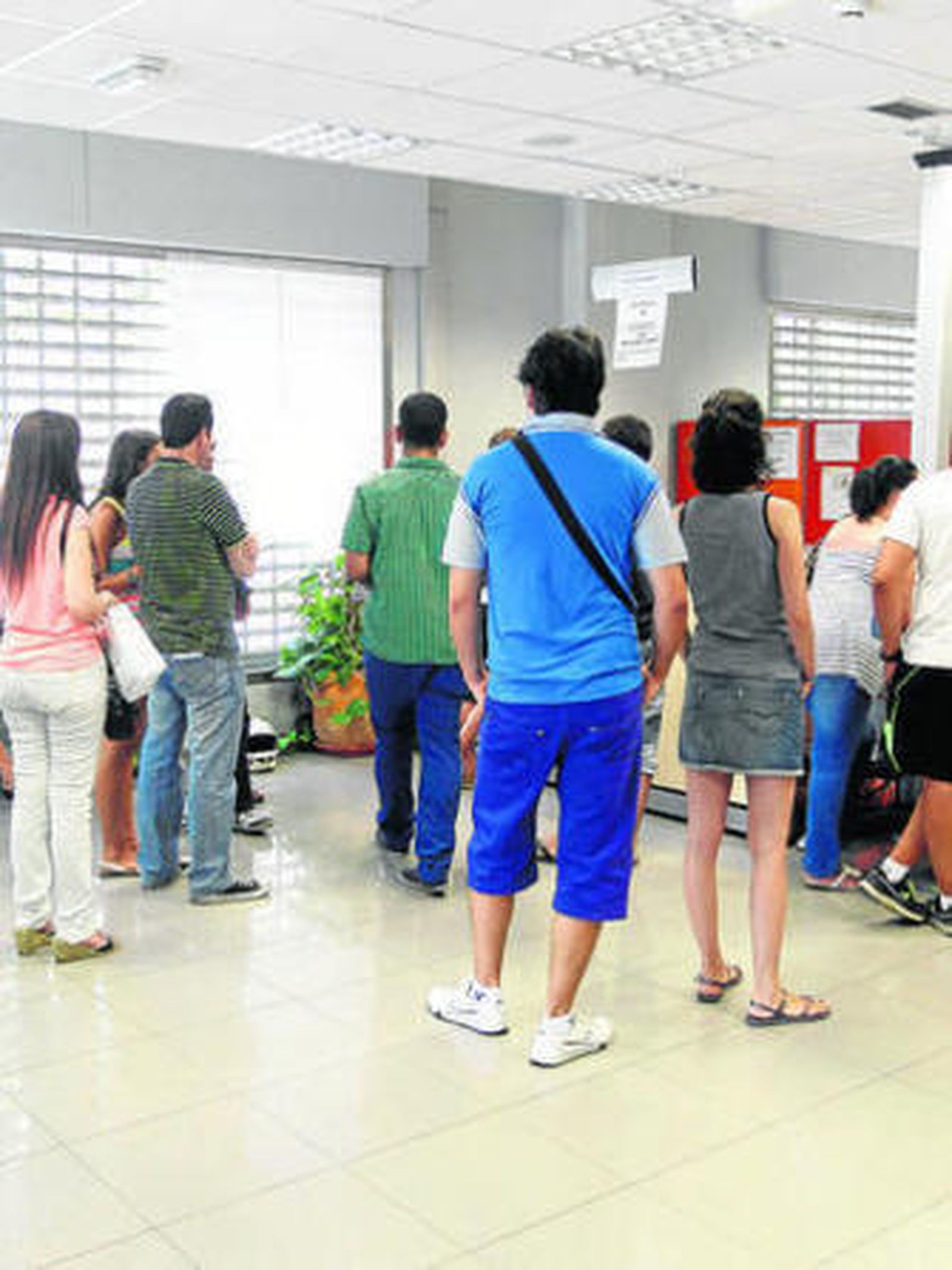 Un grupo de personas hace cola en una oficina de empleo.