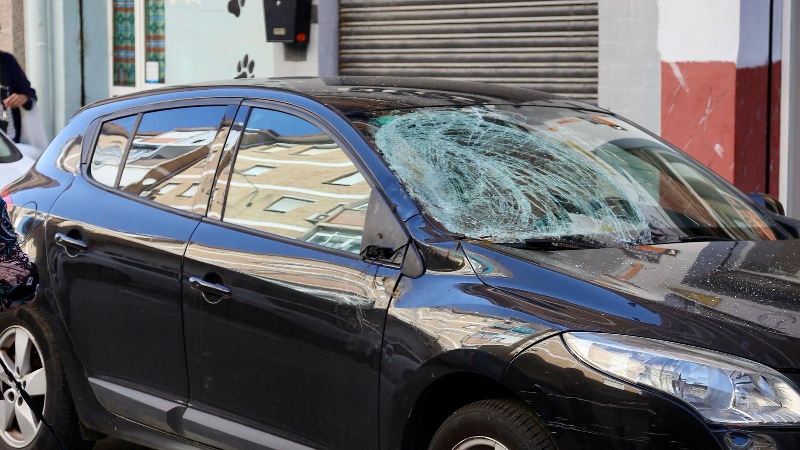 Daños en la luna delantera de un coche aparcado en la calle.