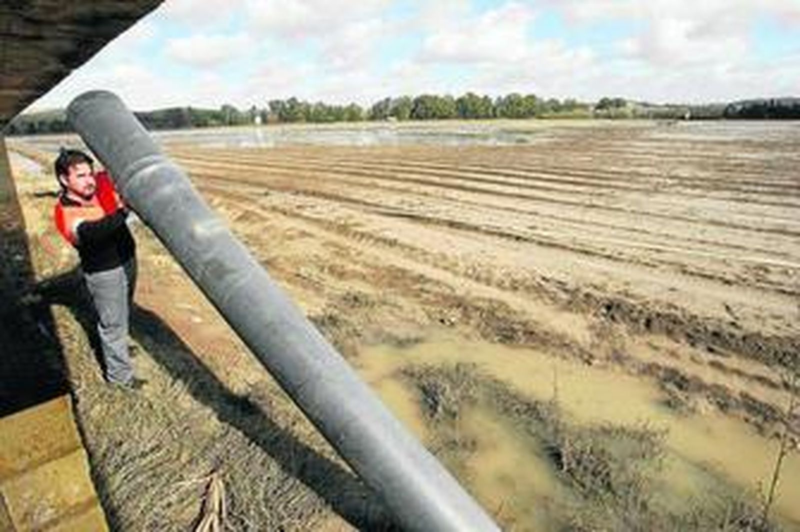 Un hombre sostiene un tubo de agua potable inutilizado debido a las inundaciones en la barriada rural de La Ina, en Jerez.