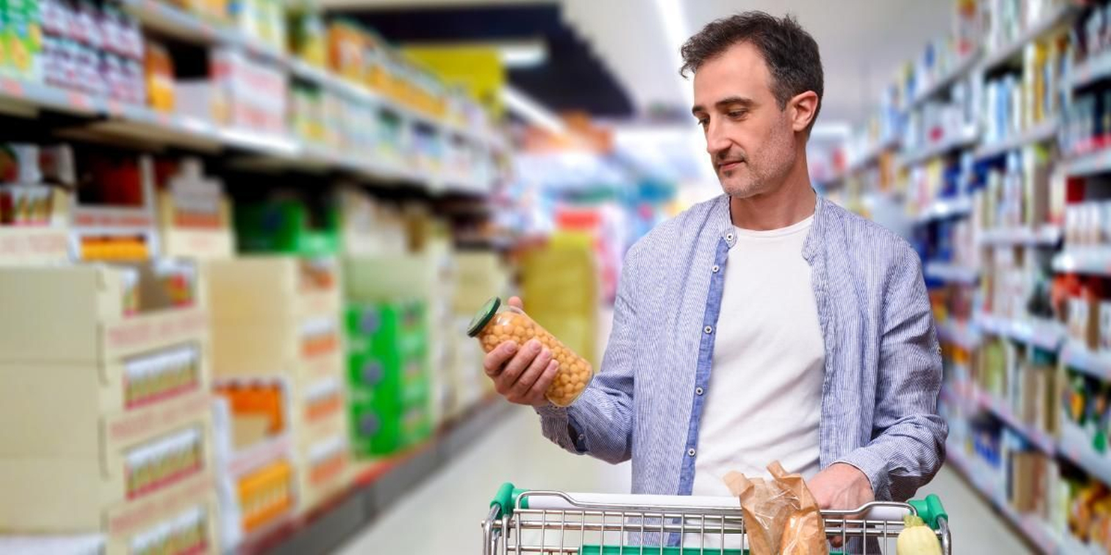 Un hombre consulta la fecha de caducidad de un producto antes de añadirlo a su carrito en el supermercado
