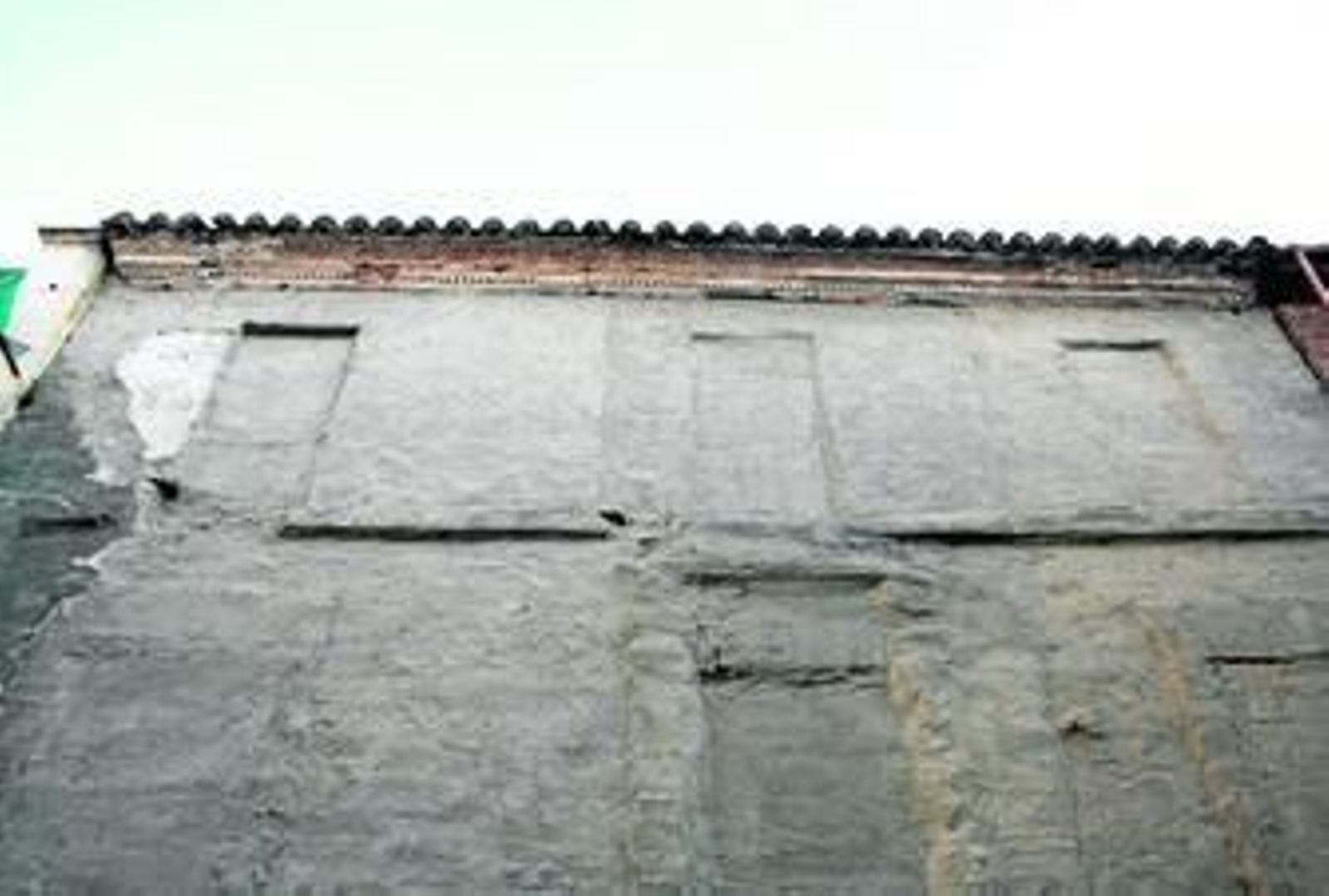 Detalle de la fachada de la casa de tres plantas con cubierta inclinada de teja cerámica curva.
