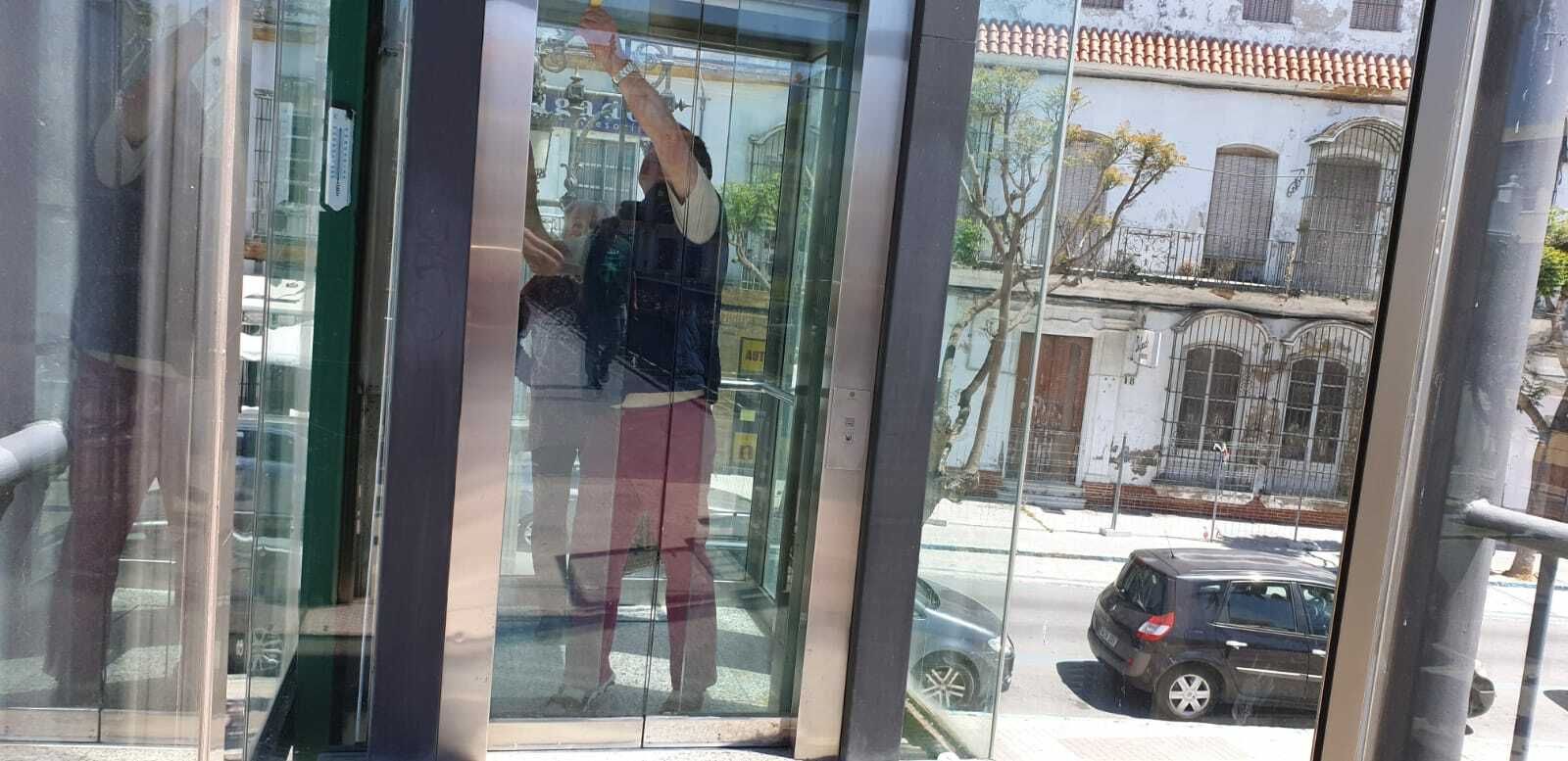 El hombre, encerrado junto a una mujer, manipula la puerta para salir de ascensor.