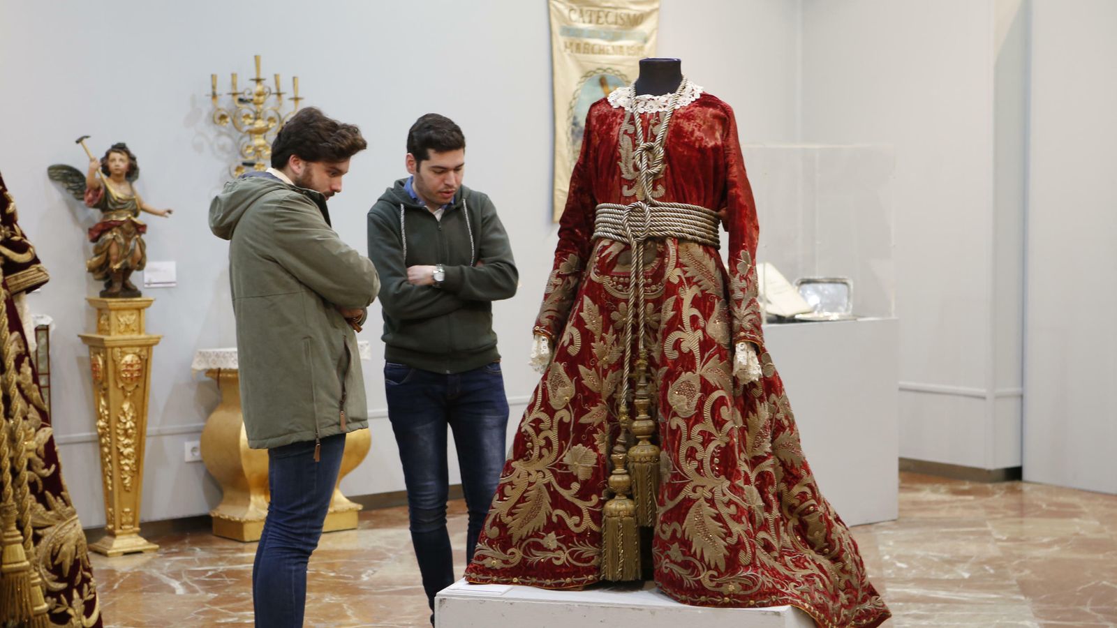Dos jóvenes observan una de las túnicas expuestas.