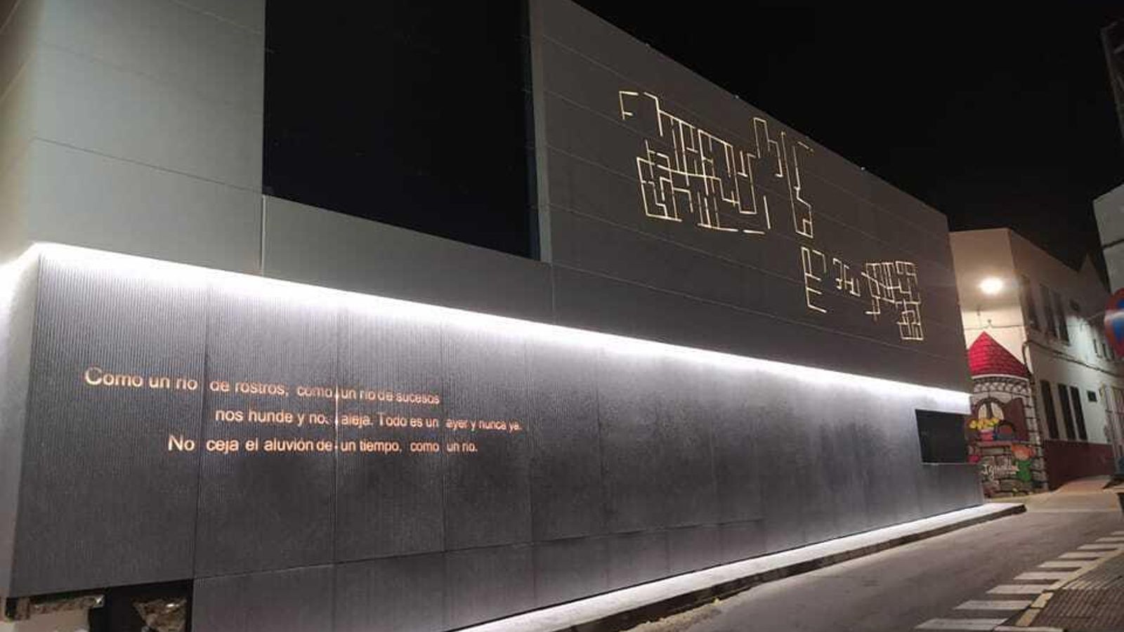 La fachada del edificio del espacio expositivo, iluminada de noche.