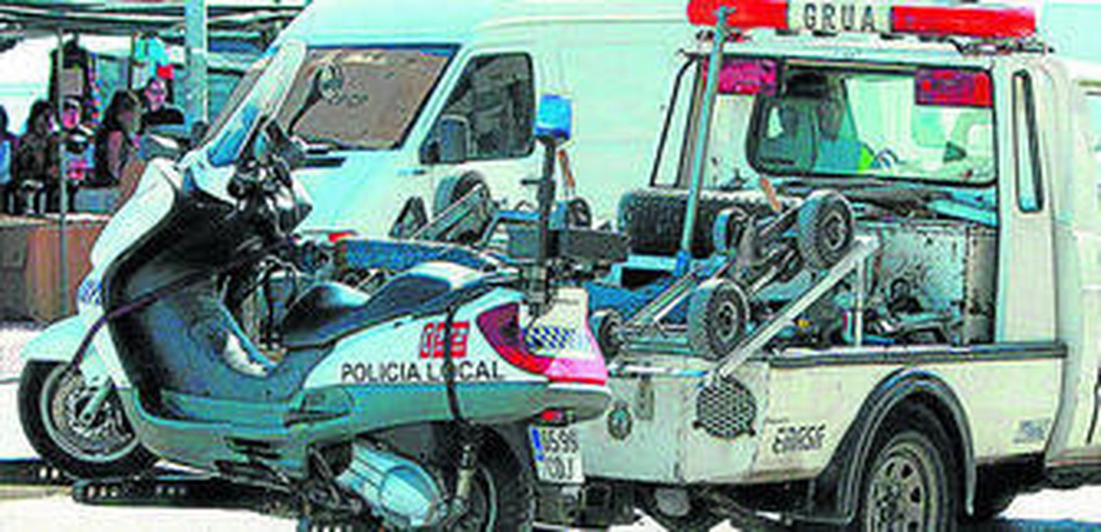 Una grúa retirando una moto de la patrulla de barrio estropeada en plena calle.