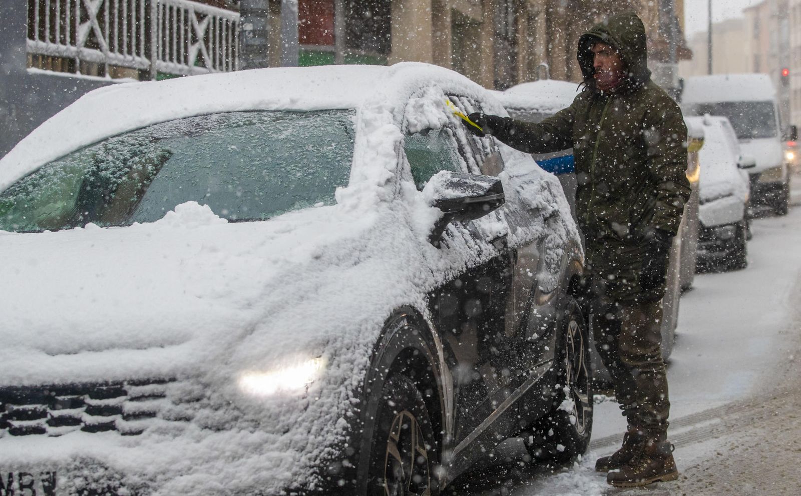 Un hombre retira la nieve de un vehículo durante la nevada de este viernes en Soria.