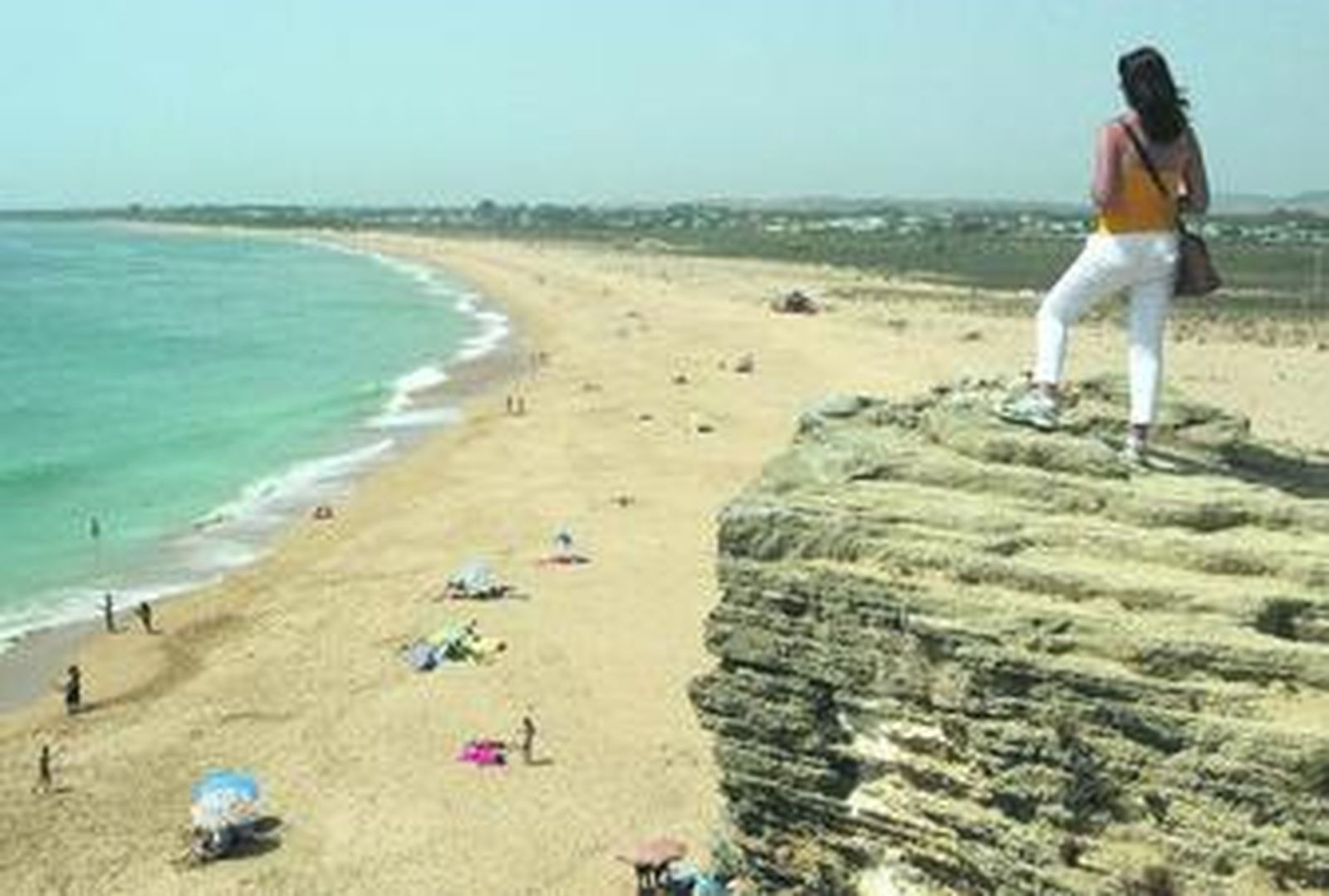 Una muchacha observa la playa de Trafalgar desde las inmediaciones del faro, en una imagen de archivo. A la derecha, suelos hoteleros.