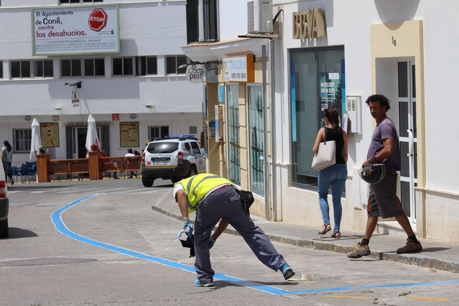 Un operario realiza el pintado en color azul de la zona de aparcamientos próxima al Ayuntamiento de Conil.