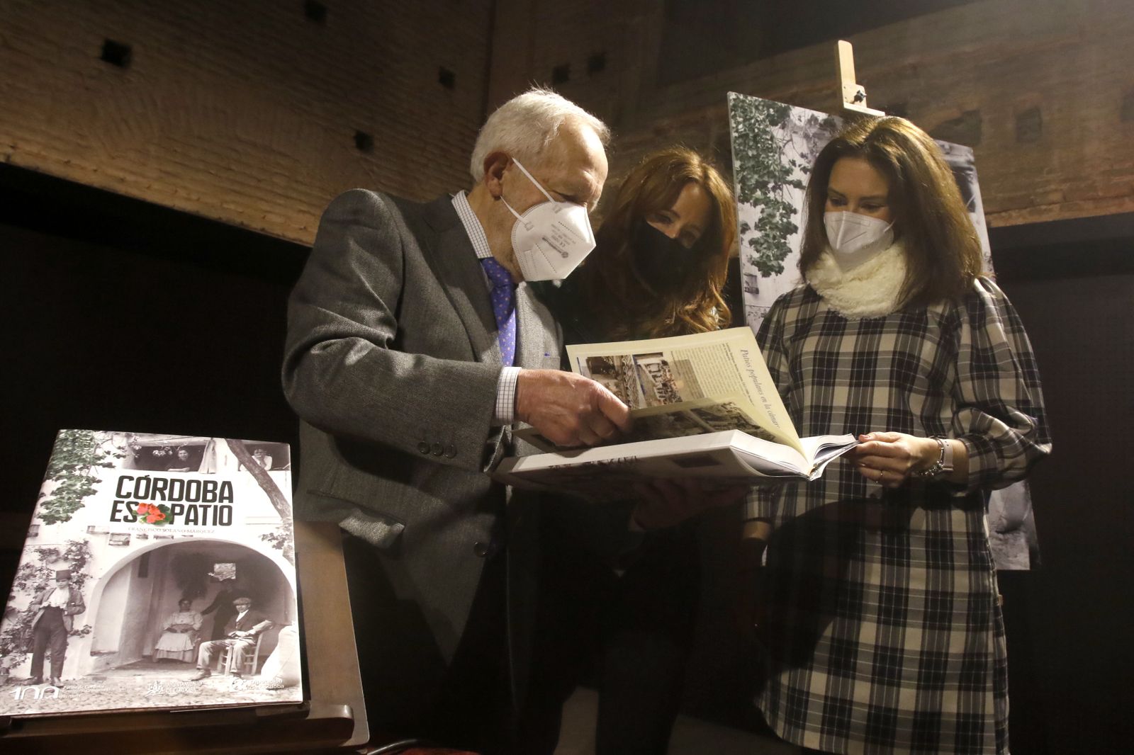 Francisco Solano Márquez ojea el libro junto a Marian Aguilar e Inmaculada Siles.