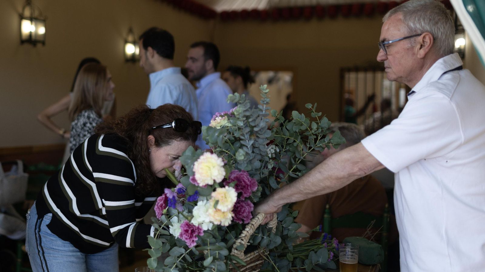 Dos personas preparan las flores del interior de unas de las casetas.