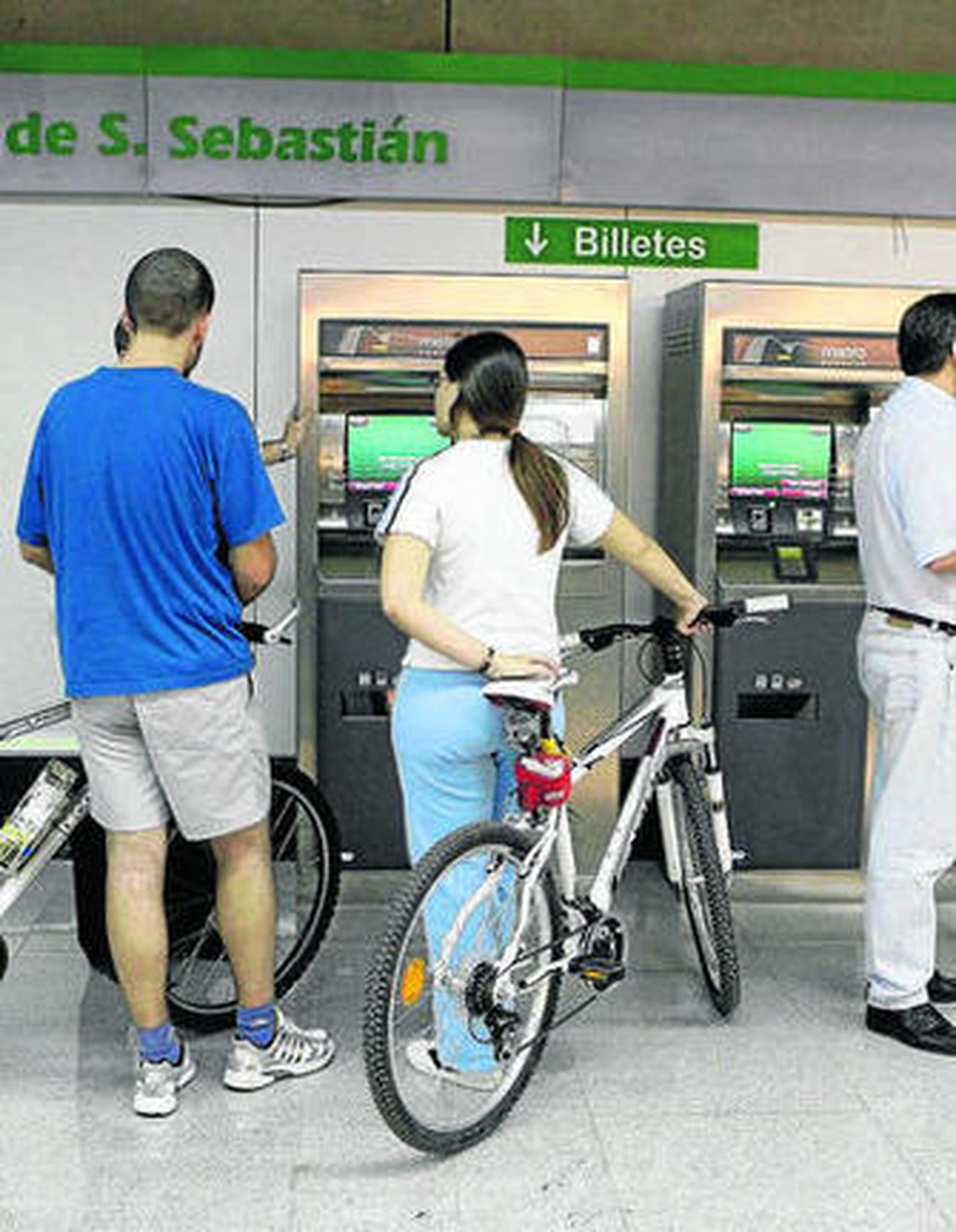 Varios usuarios en una de las máquinas expendedoras de billetes.